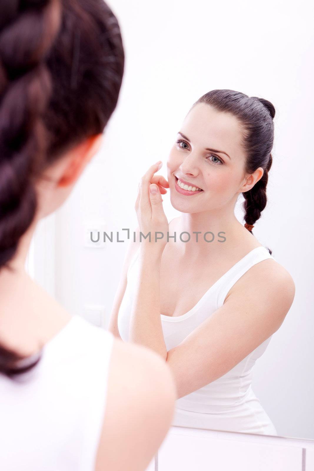 beautiful attractive woman applying cream on face skincare