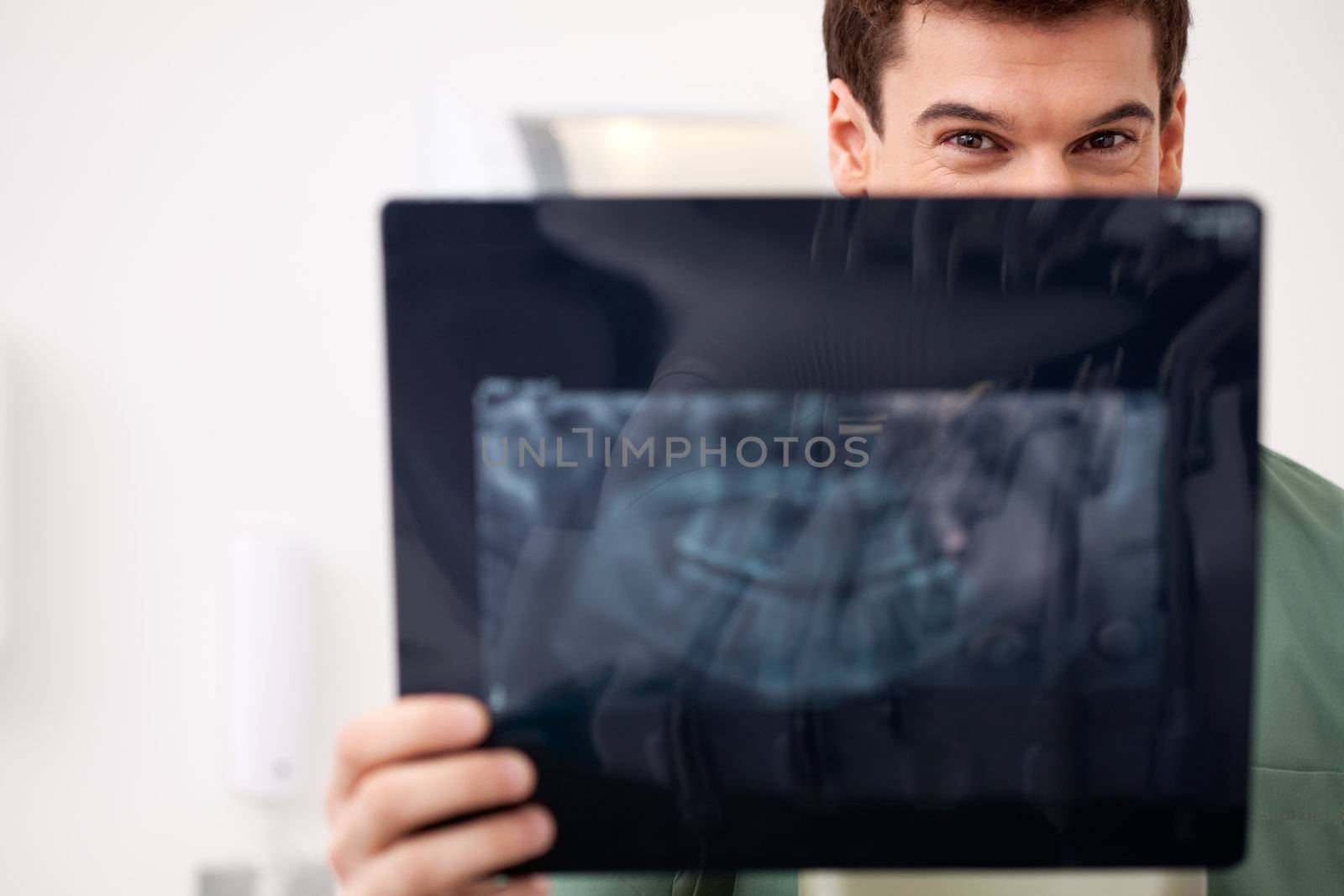 Young male dentist looking at an x-ray, eyes visiable over top