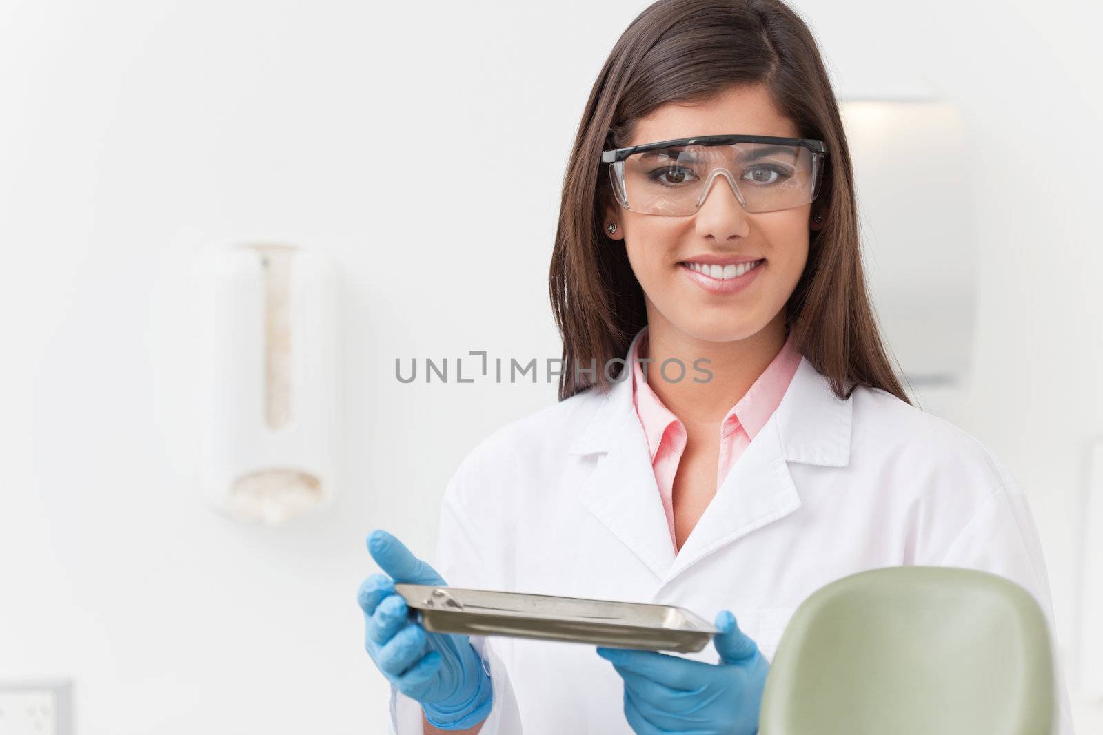 Smiling beautiful dentist holding tray of dental instruments