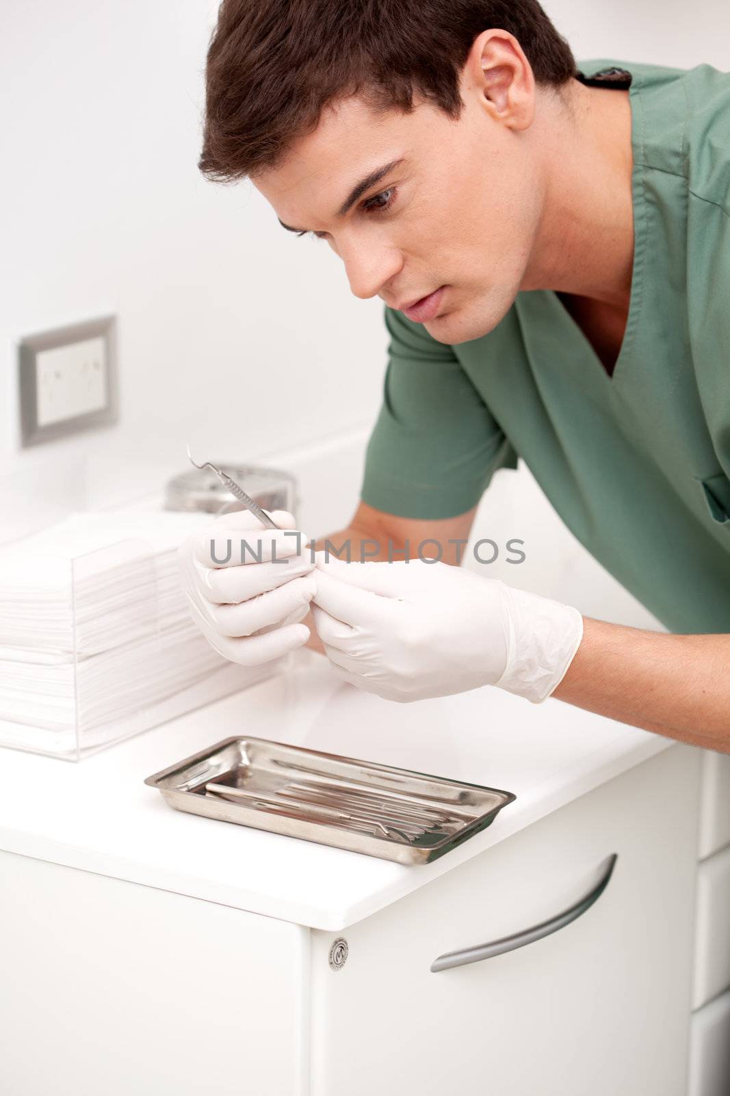 Young male dentist inspecting sterile dentistry tool