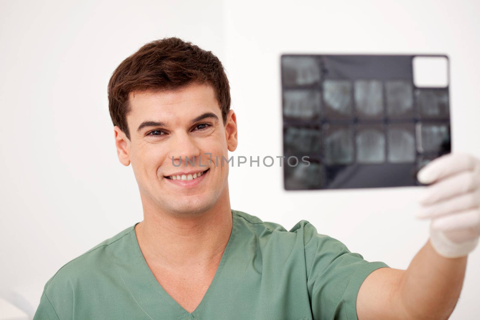 A smiling happy dentist holding x-rays, looking at the camera