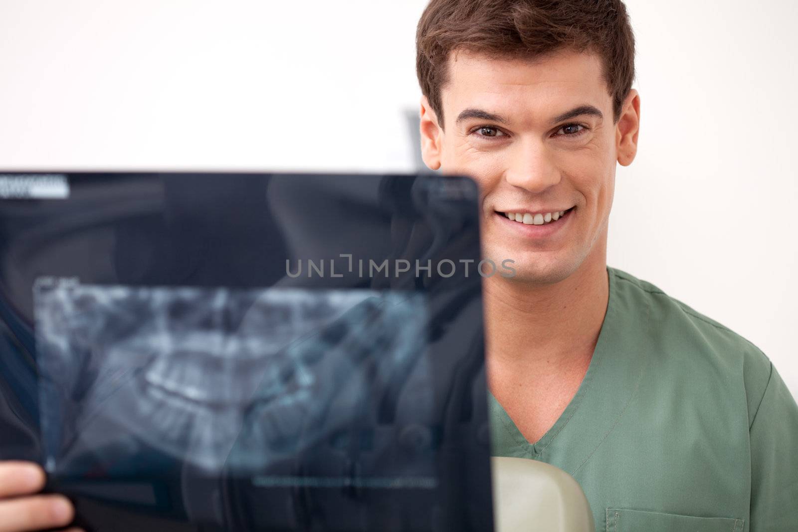Young happy man dentist smiling looking at the camera holding an x-ray