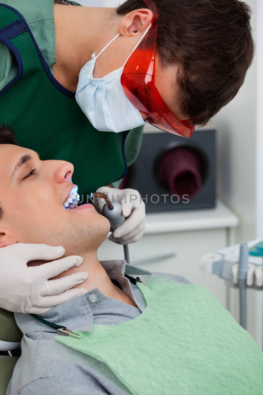 Male orthodontist working on male patient with ultraviolet light