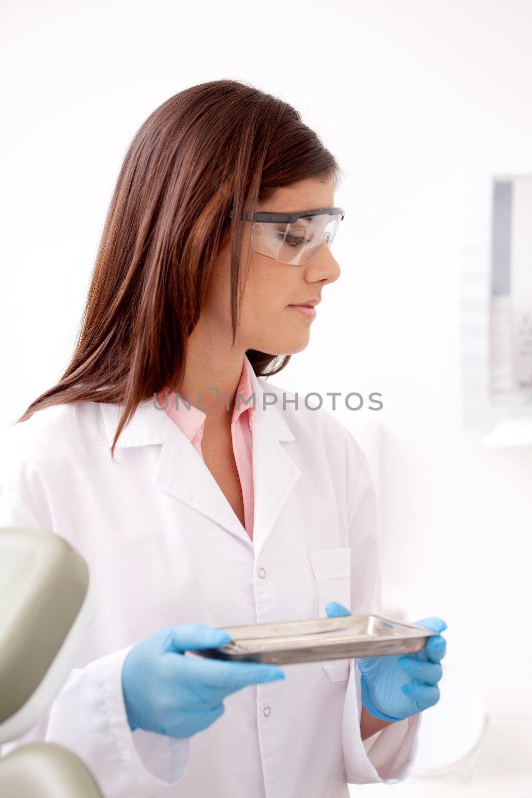 Dentist holding stainless steel tray of sterile tools