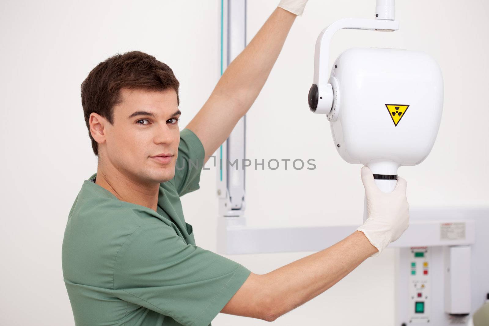 Dentist adjusting x-ray equipment, looking at the camera with a slight smile