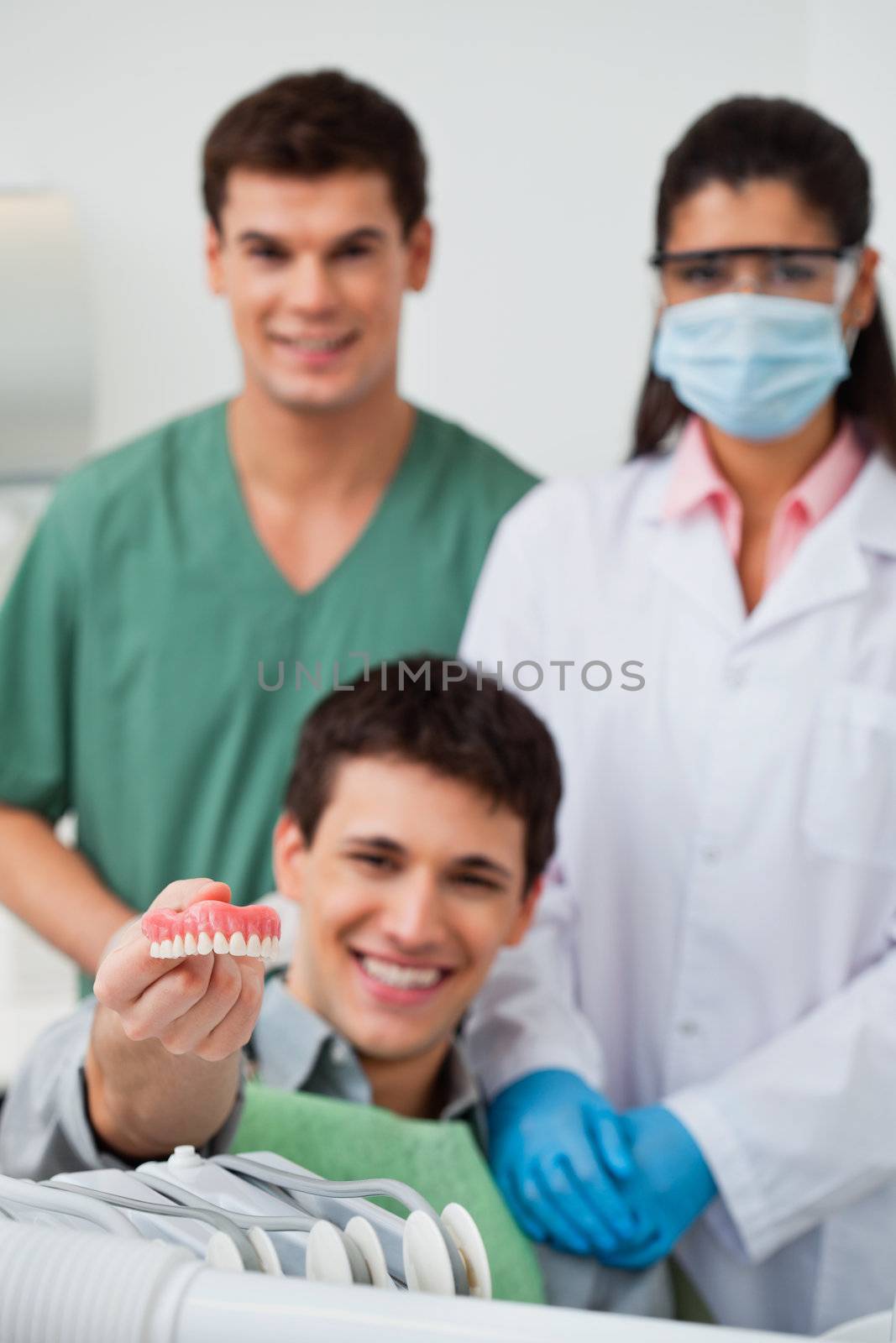 Male patient showing dental molds with dentist standing in background with her colleague