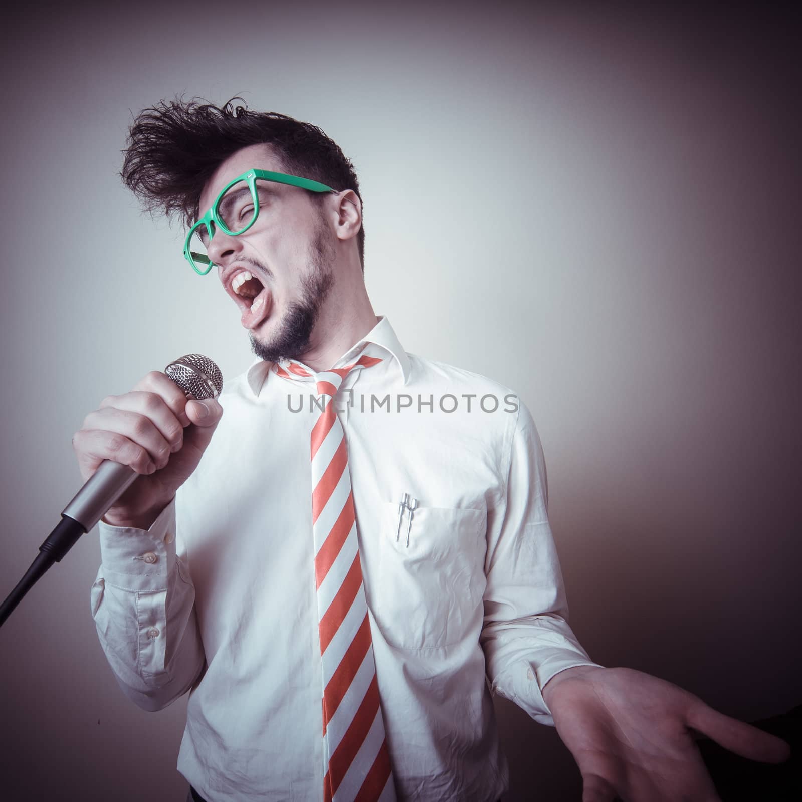 funny stylish businessman singing on gray background