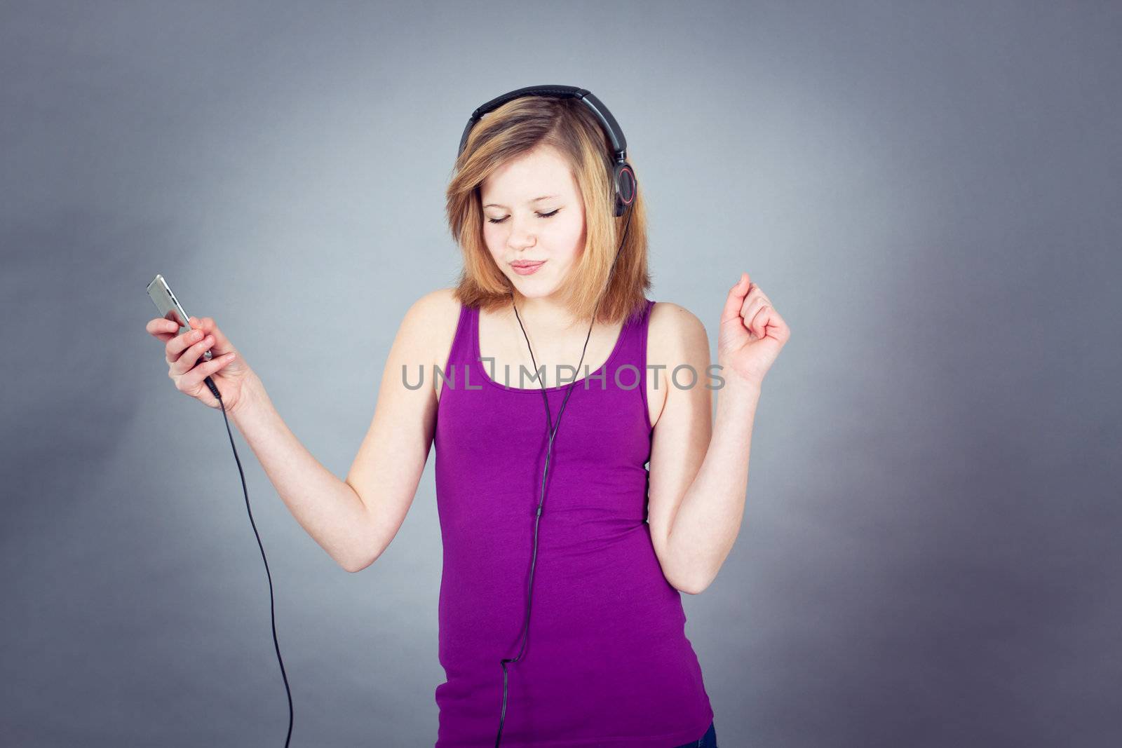 young smiling teenager girl dancing with mp3 player and earphones listening to music