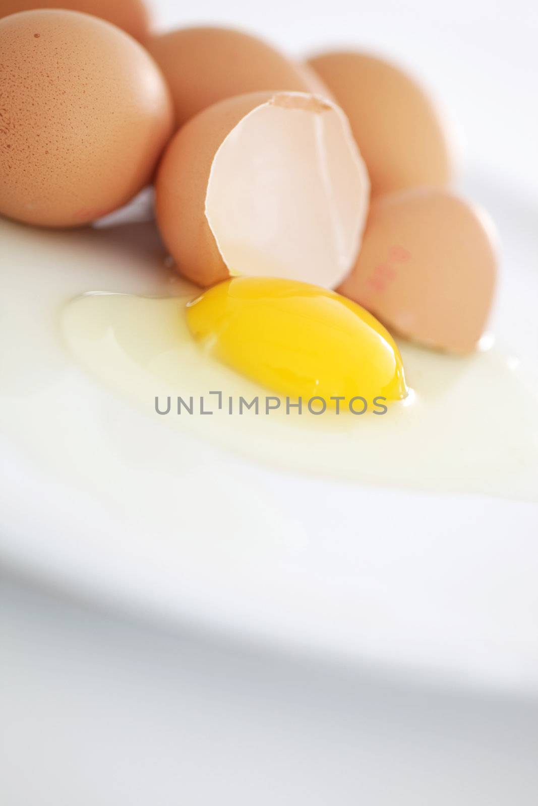 One broken egg in the foreground on a plate by Farina6000