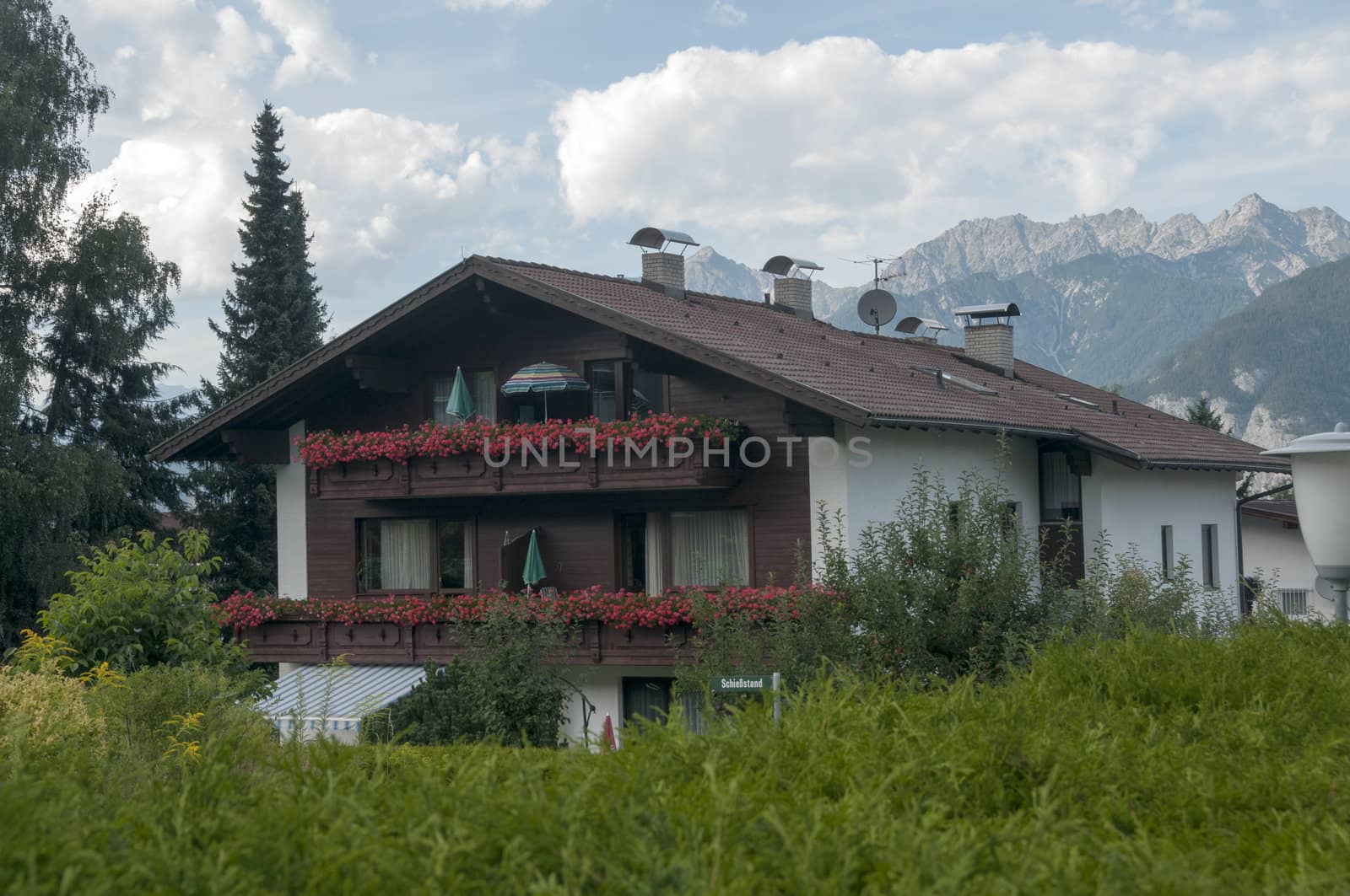 traditonal house in austria with red geranium flowers on the balcony