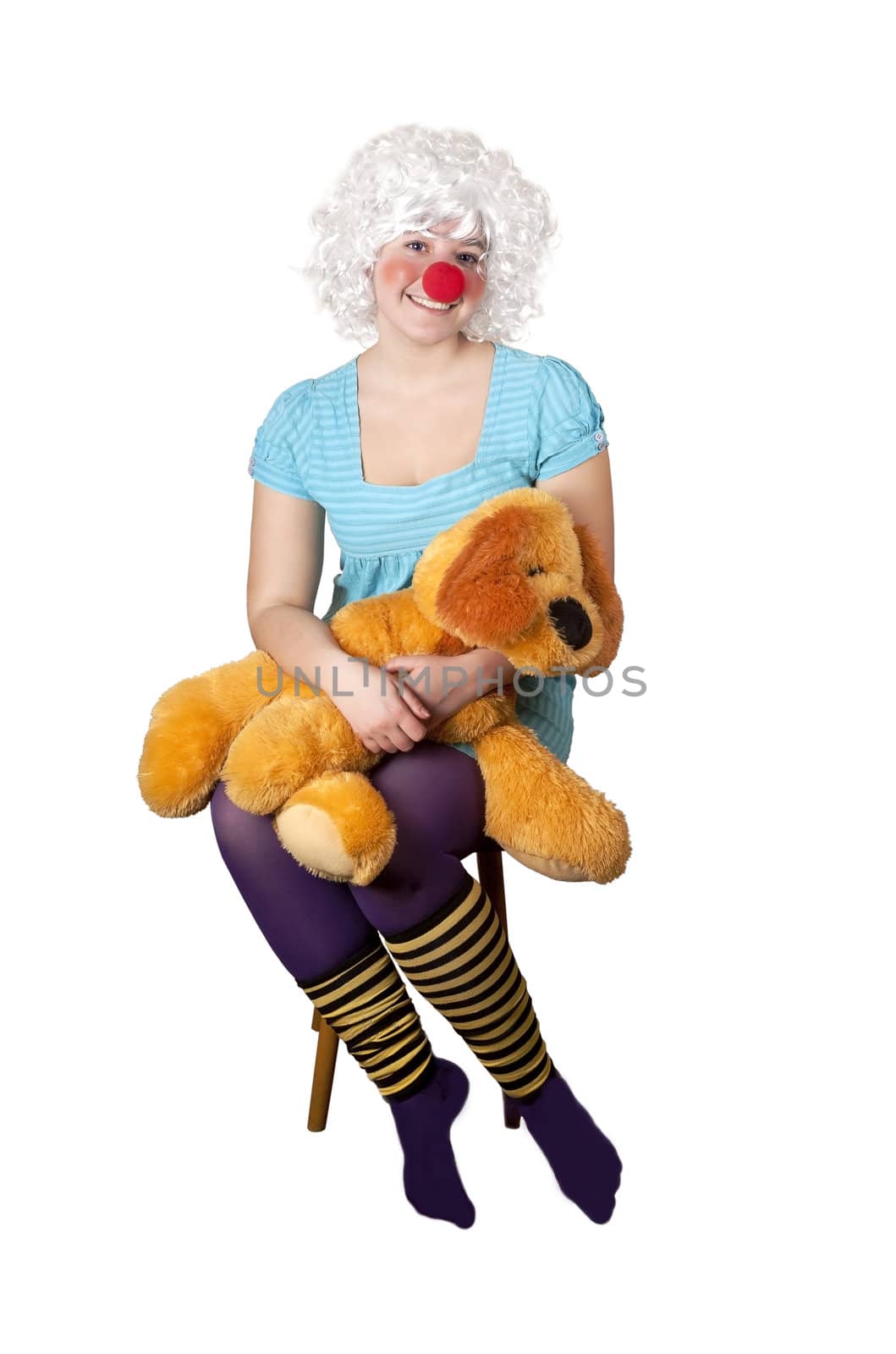 A smiling girl sitting and holding a child's stuffed toy on a white background