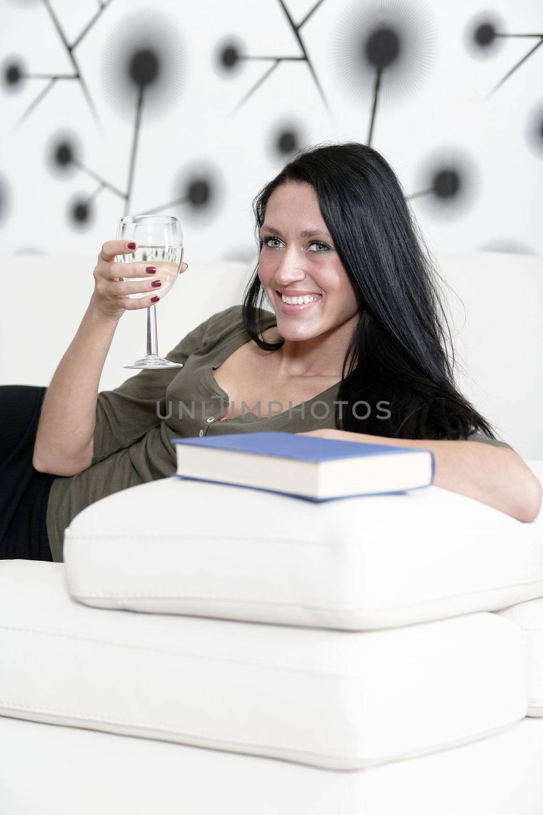 Woman relaxing with a book and wine by studiofi