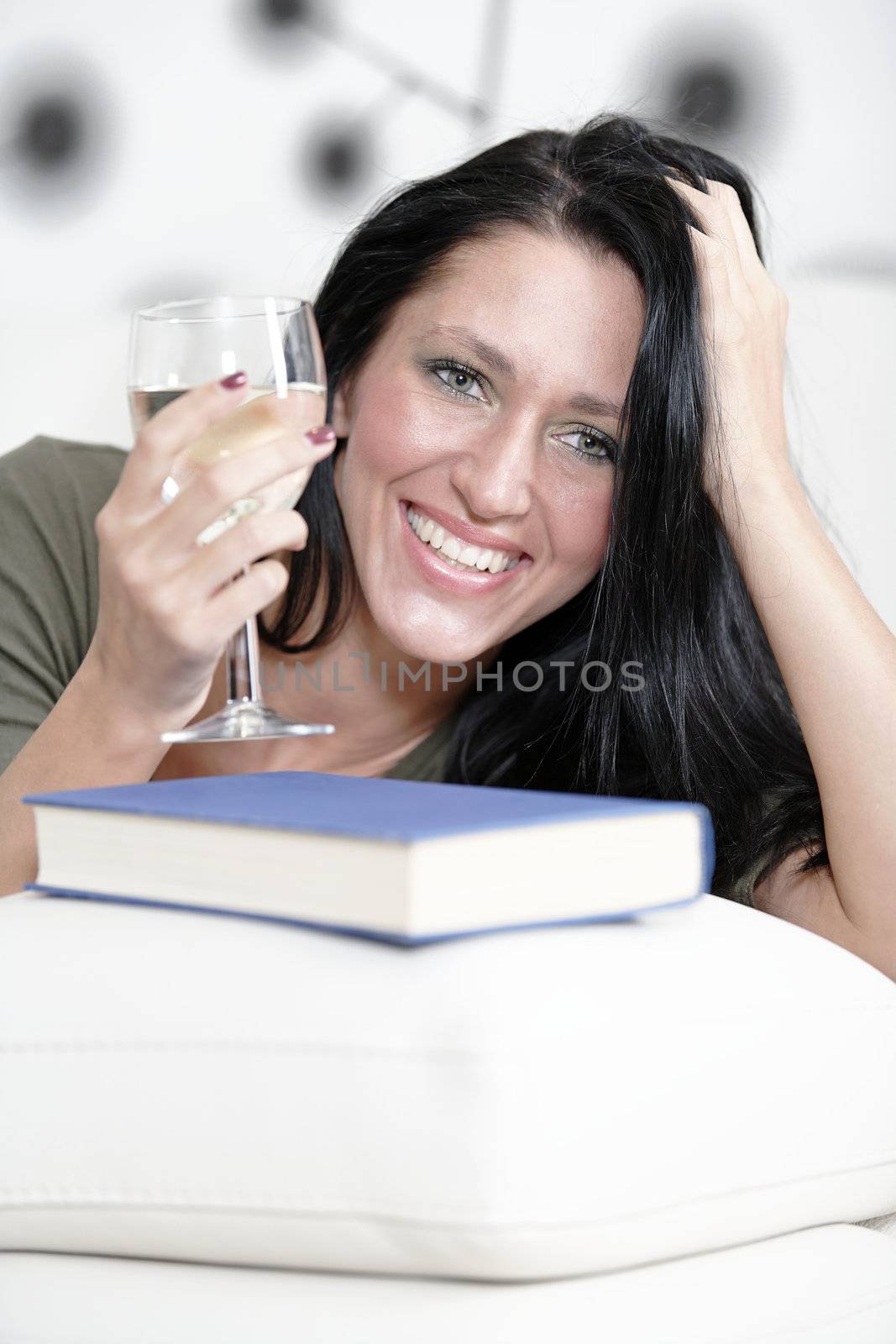 Woman relaxing with a book and wine by studiofi