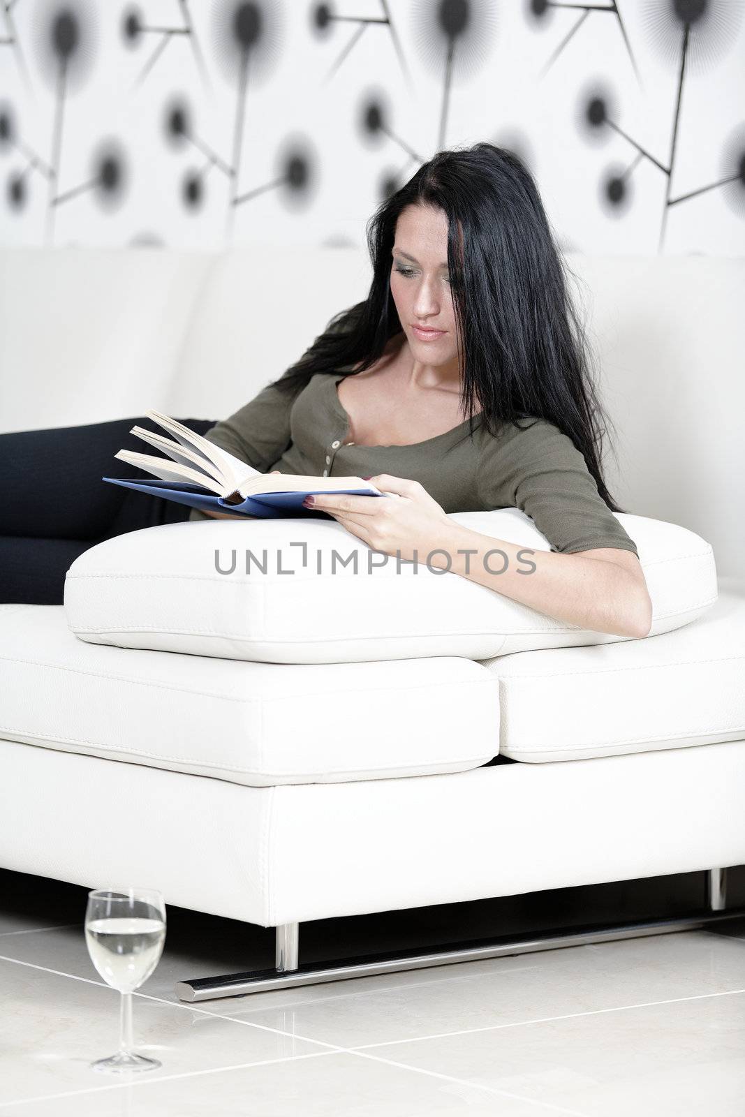 Woman relaxing with a book and wine by studiofi