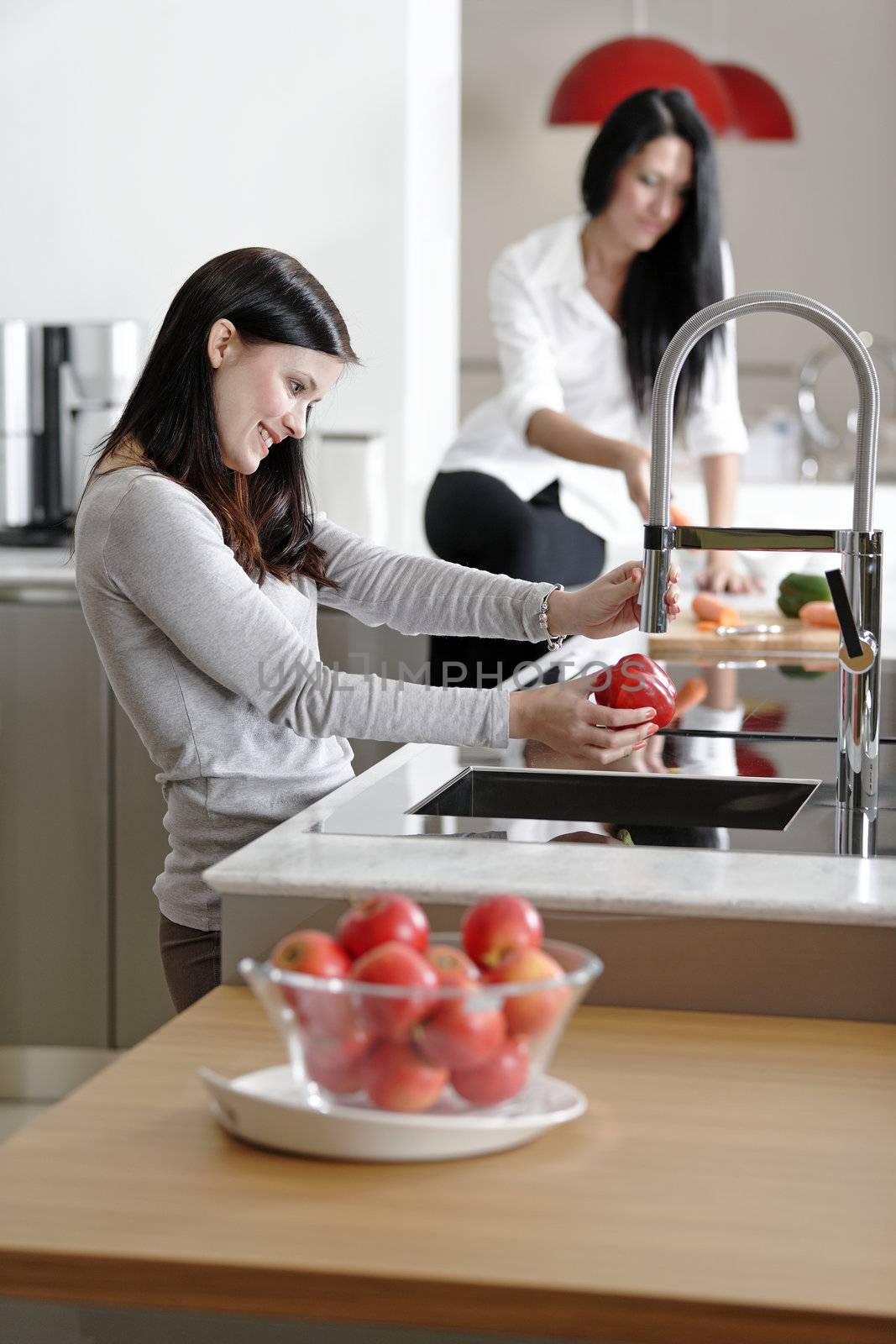 Two attractive friends preparing food in their kitchen at home.