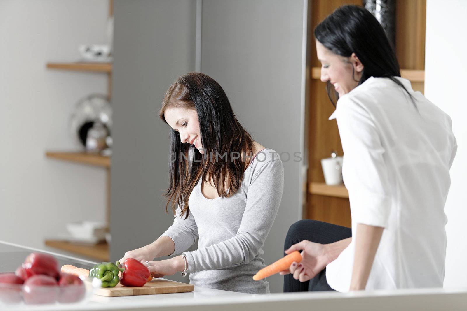 Two attractive friends preparing food in their kitchen at home.