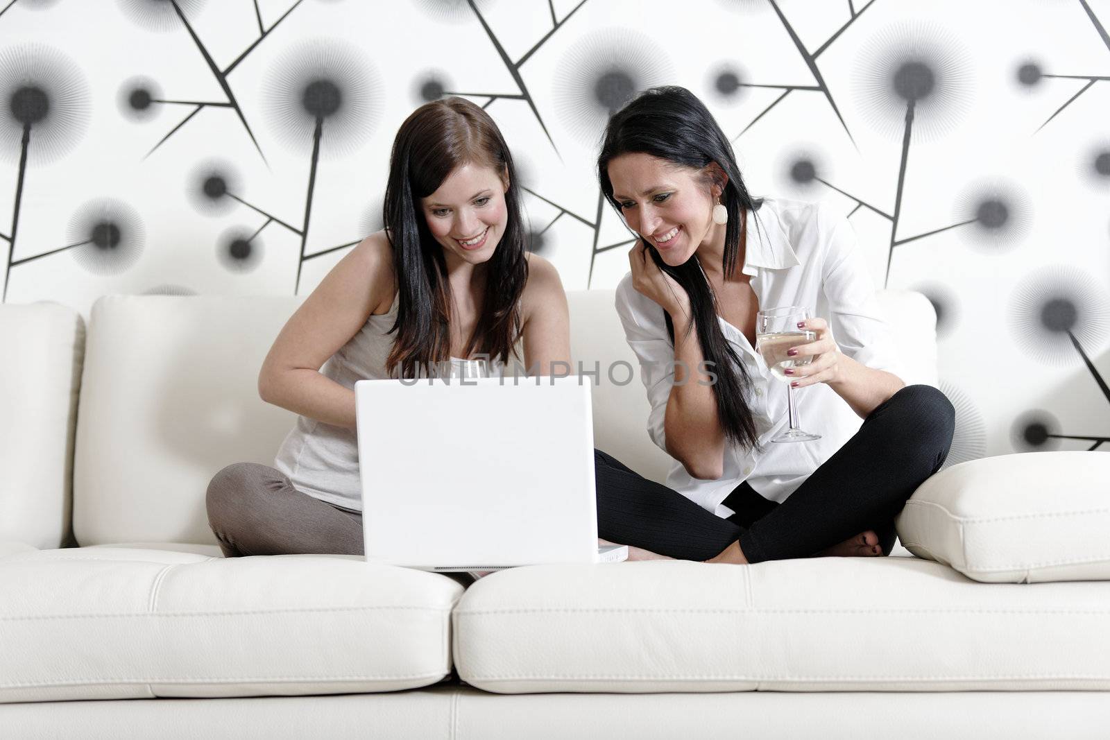 Two friends on a laptop at home by studiofi