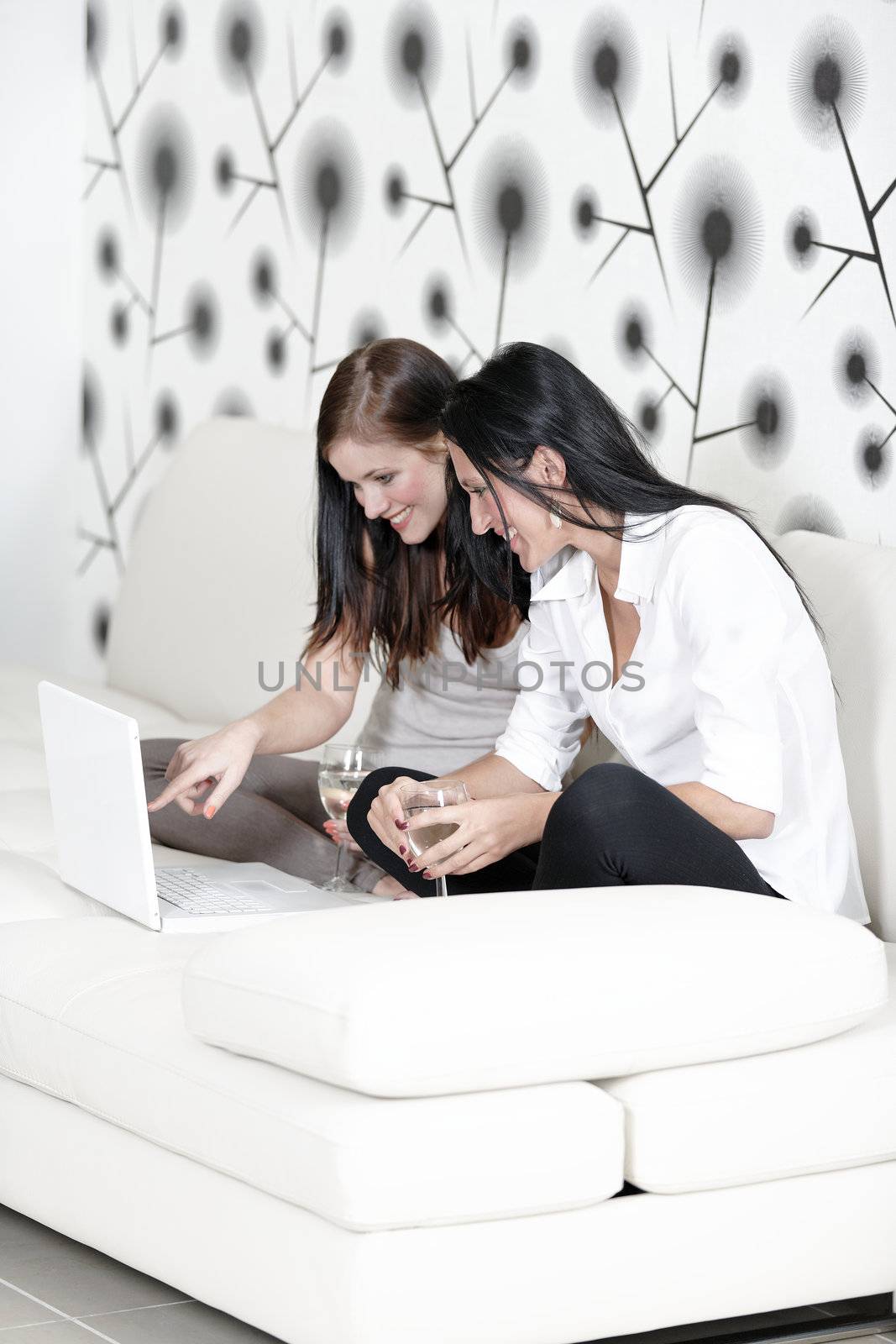 Two friends on a laptop at home by studiofi