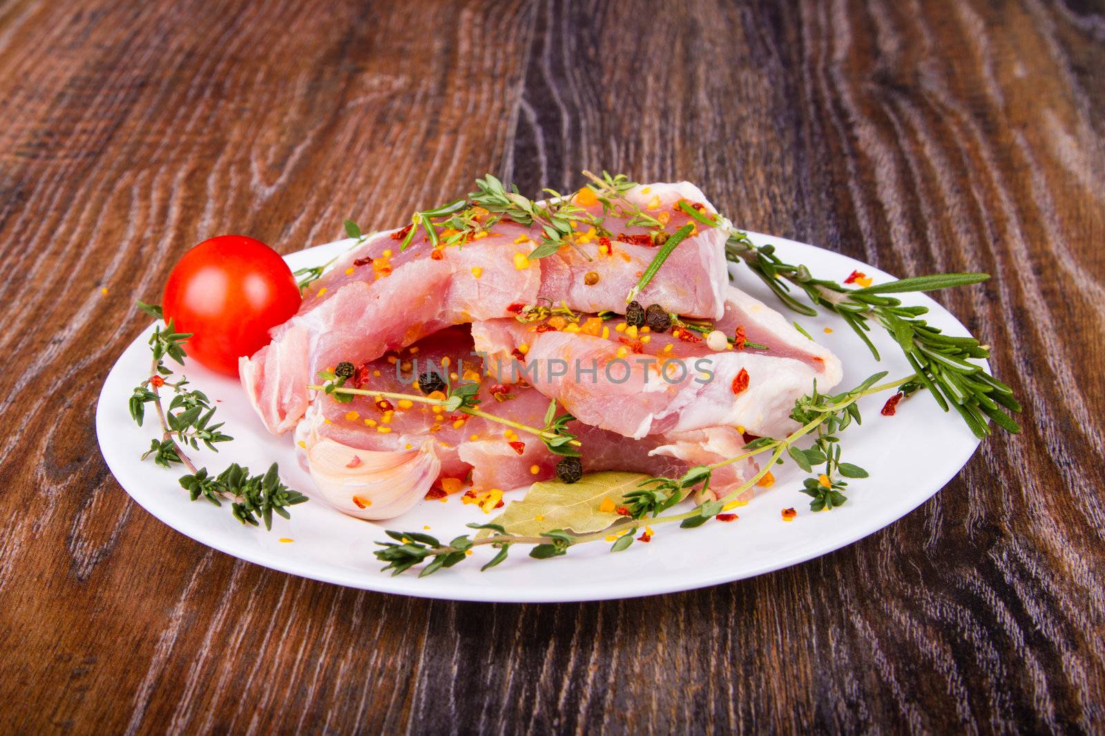 Raw fresh meat on a plate with condiments and fresh vegetables