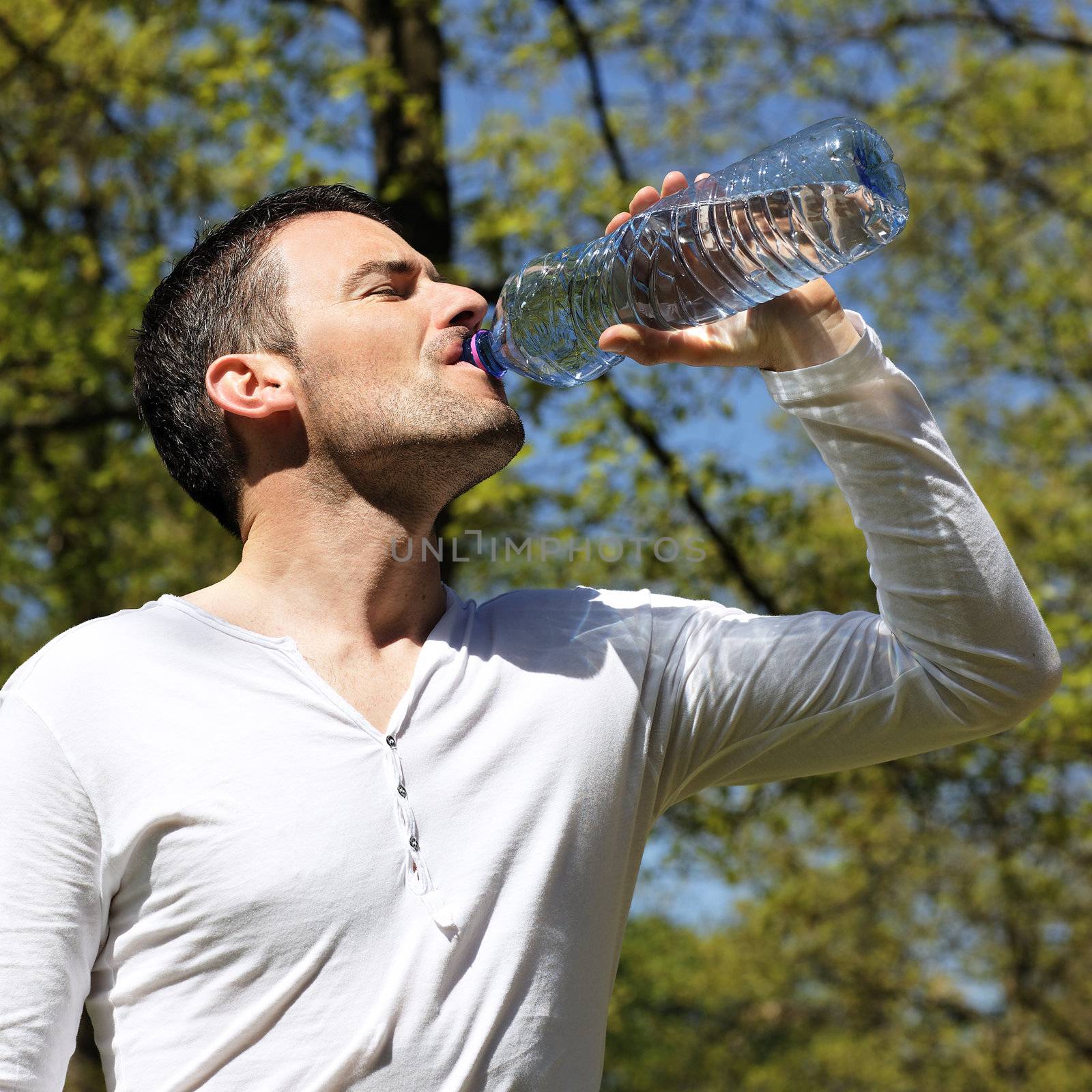 handsome man drinking water in a park