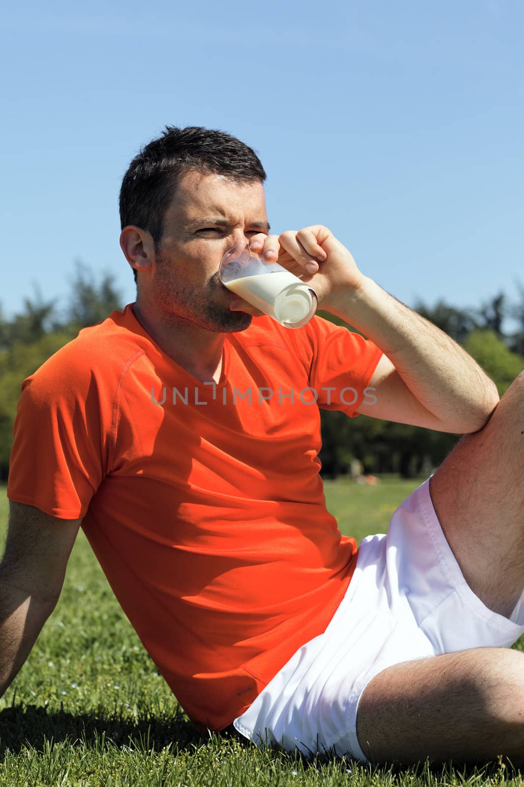 man drinking glass of milk in a park