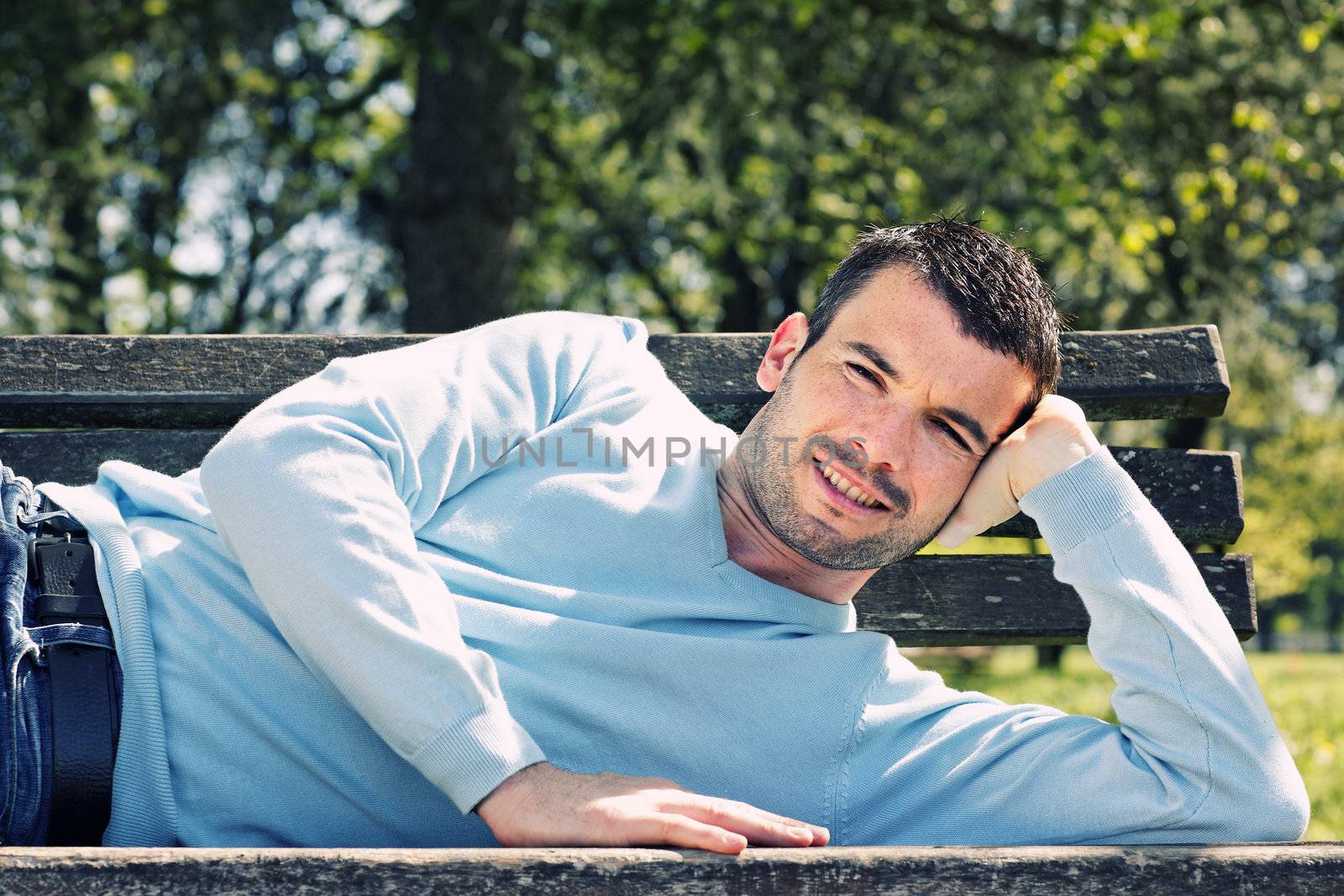 relaxed handsome man on a bench in a park