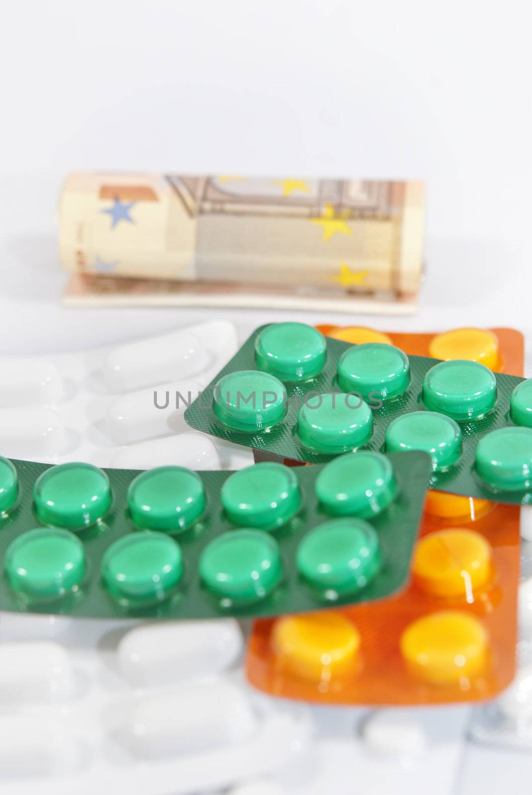 Pills and money (euros banknotes) on white background