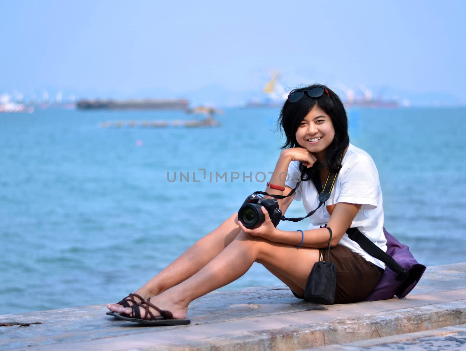 Young woman taking pictures on the beach  by siraanamwong