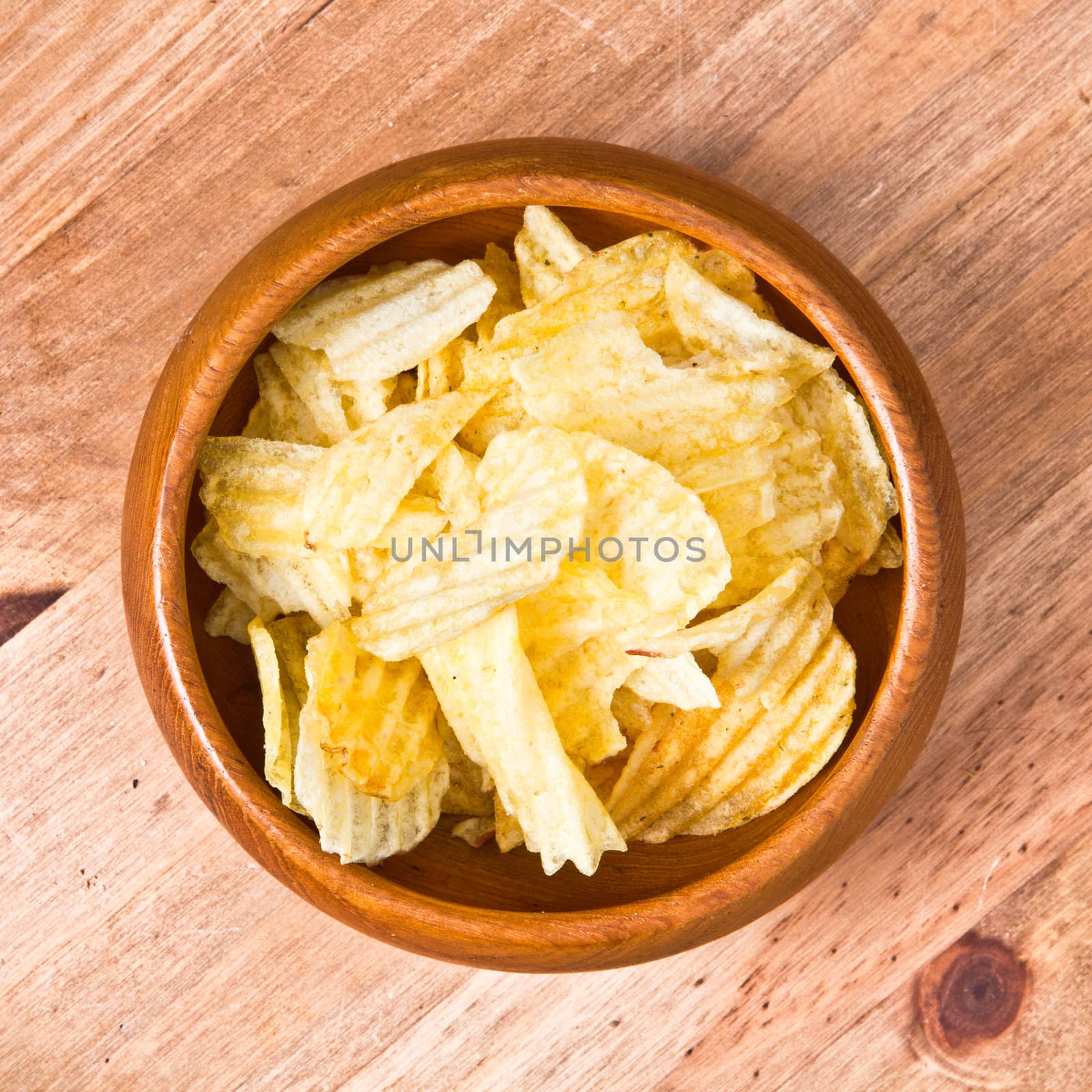 bowl of potato crisps on a wooden table