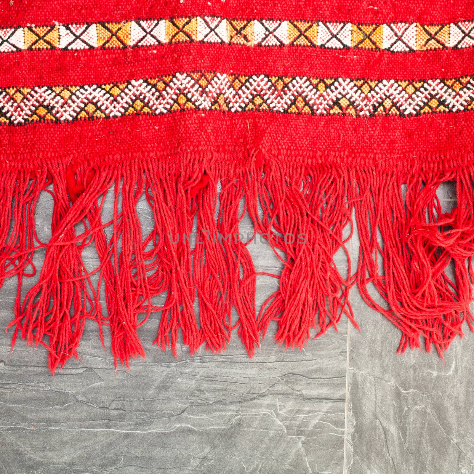 Edge of a bright red kilim rug on the floor