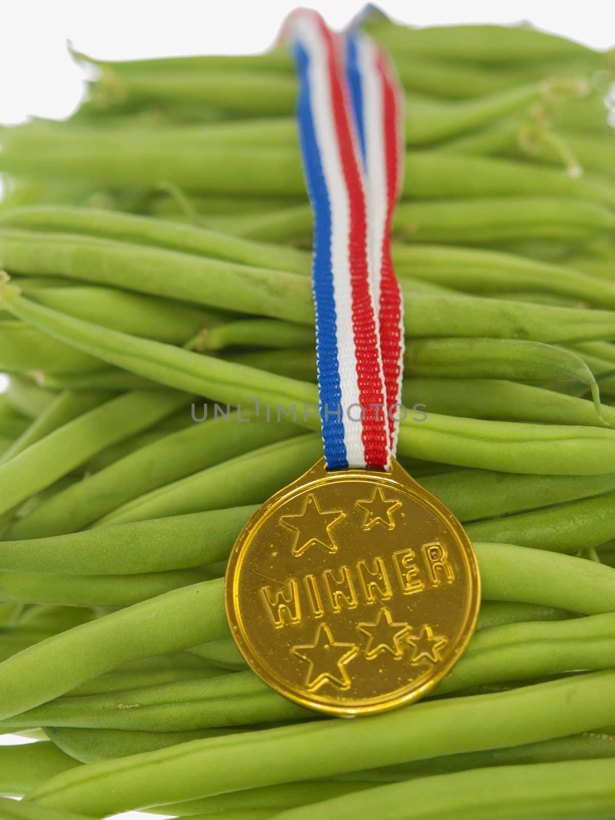 green beans with a gold medal winner pendant on a wooden background