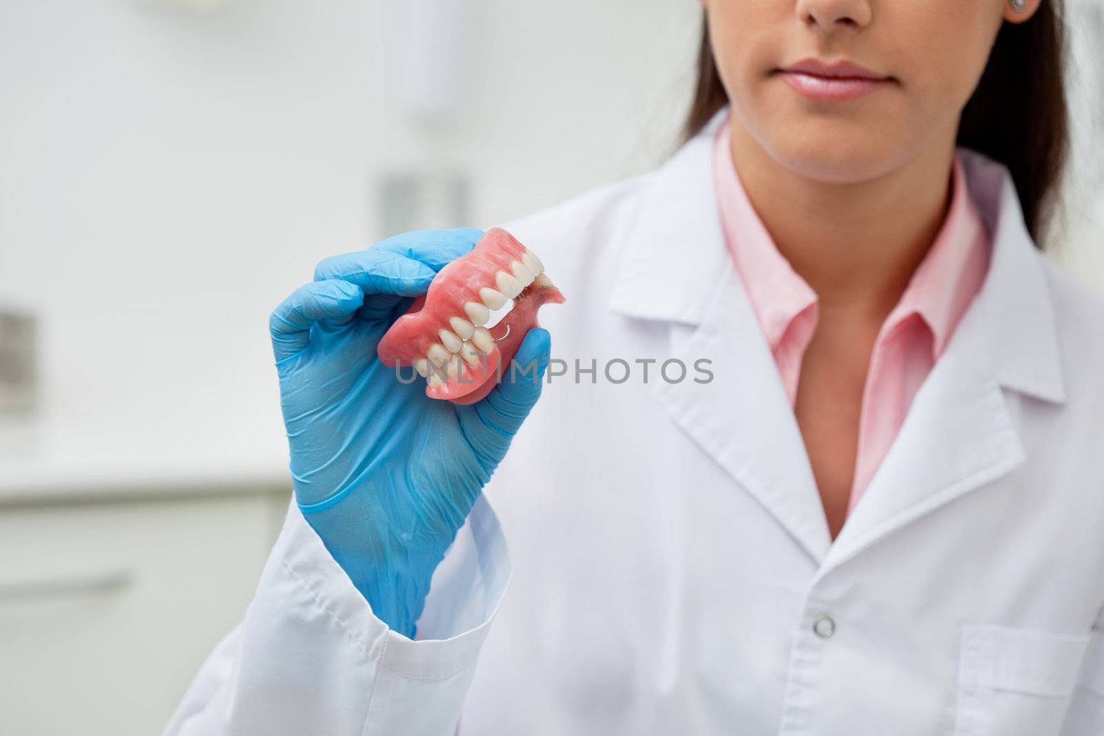 Female dentist holding dental mold at clinic