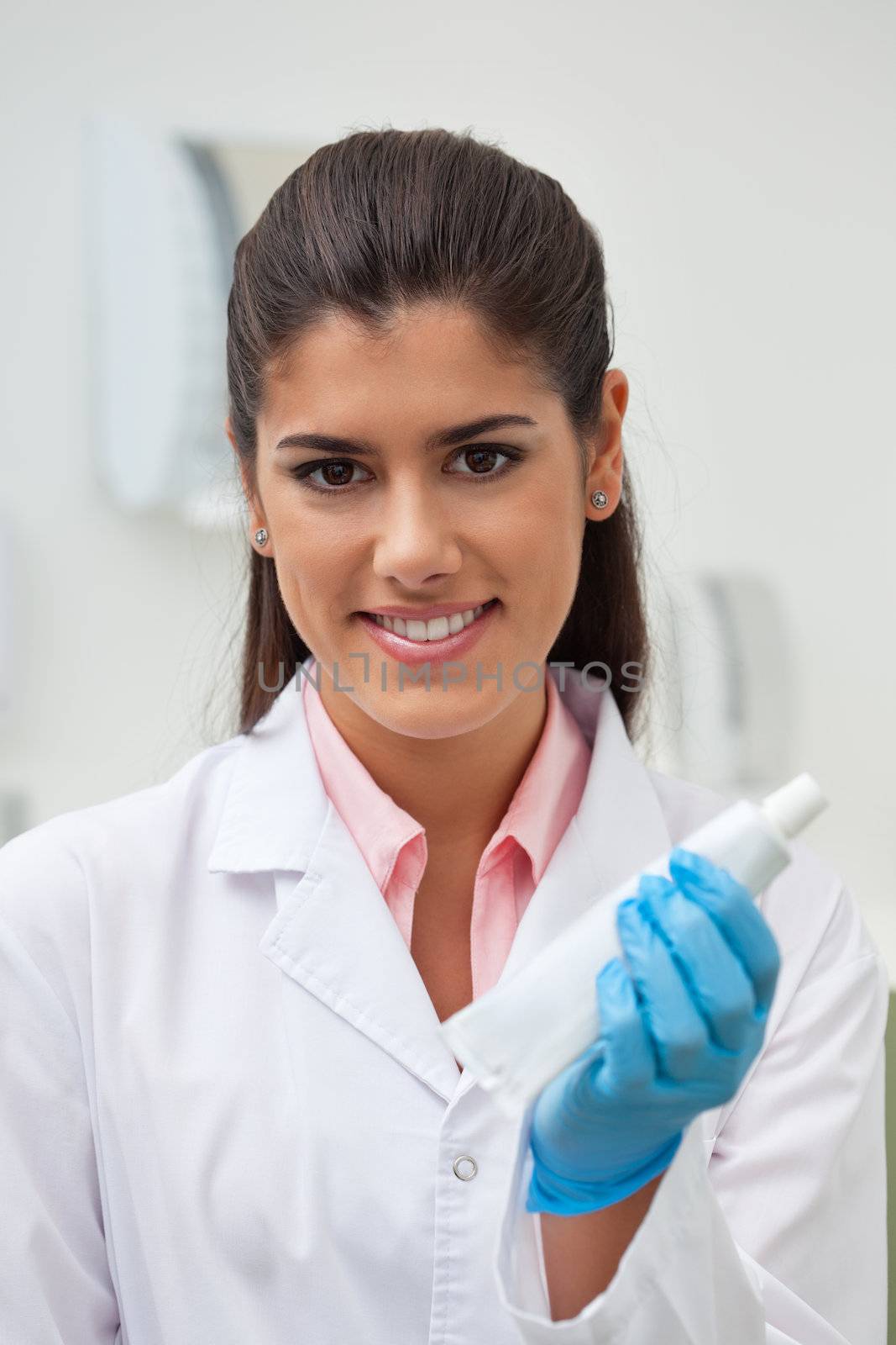 Female dentist holding toothpaste by leaf