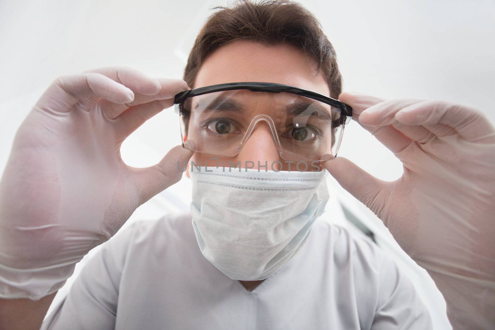 Close-up of young dentist adjusting his eyewear