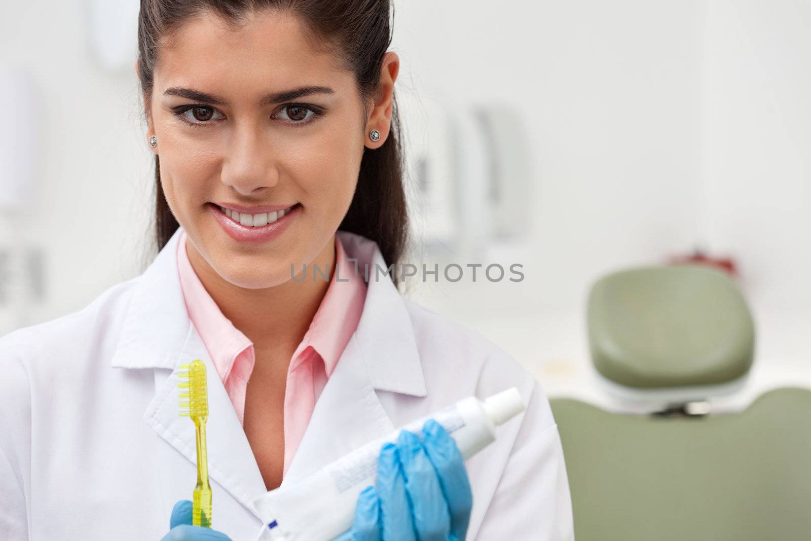 Portrait of female dentist holding toothbrush and toothpaste
