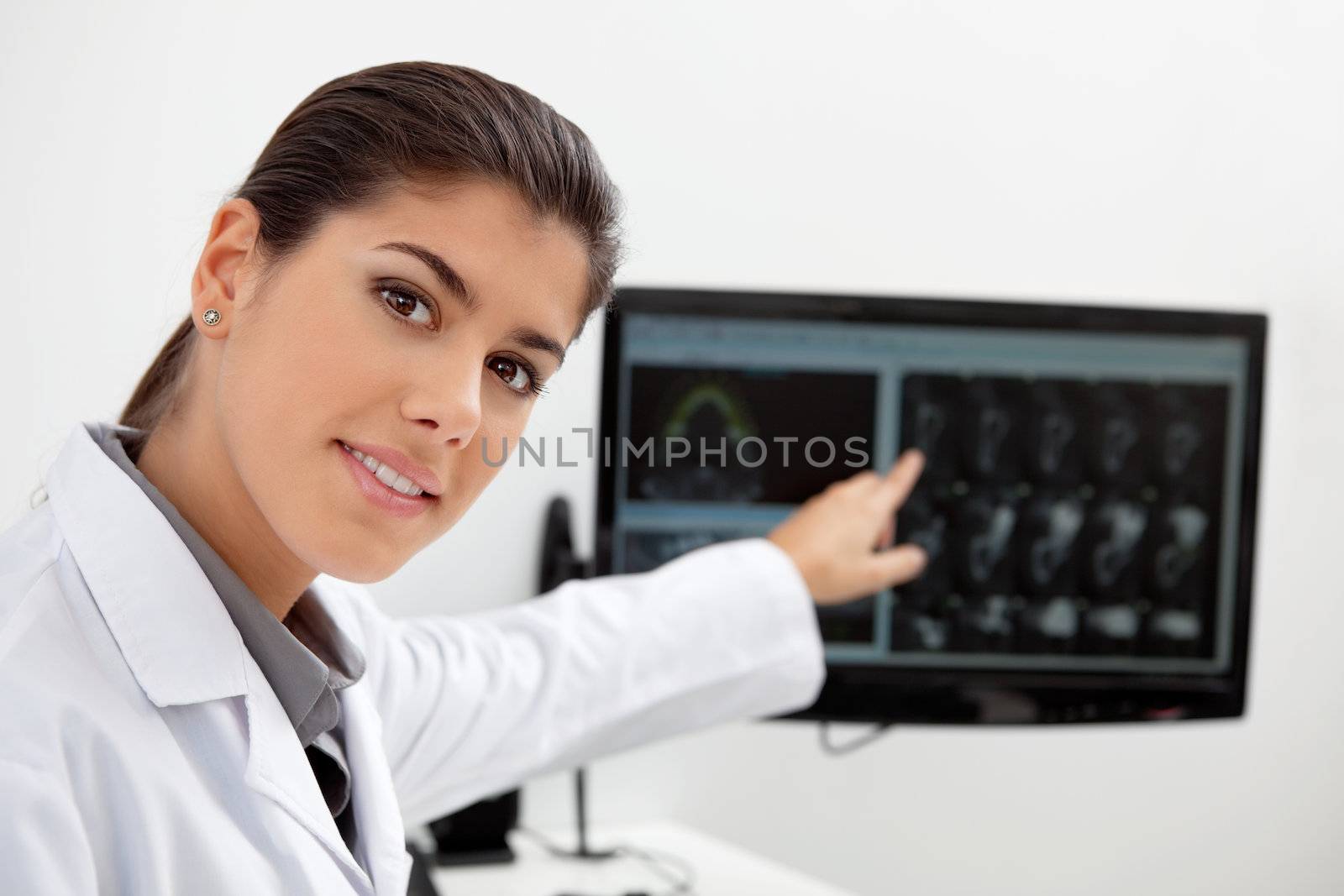 Portrait of pretty female dentist showing teeth x-ray on screen