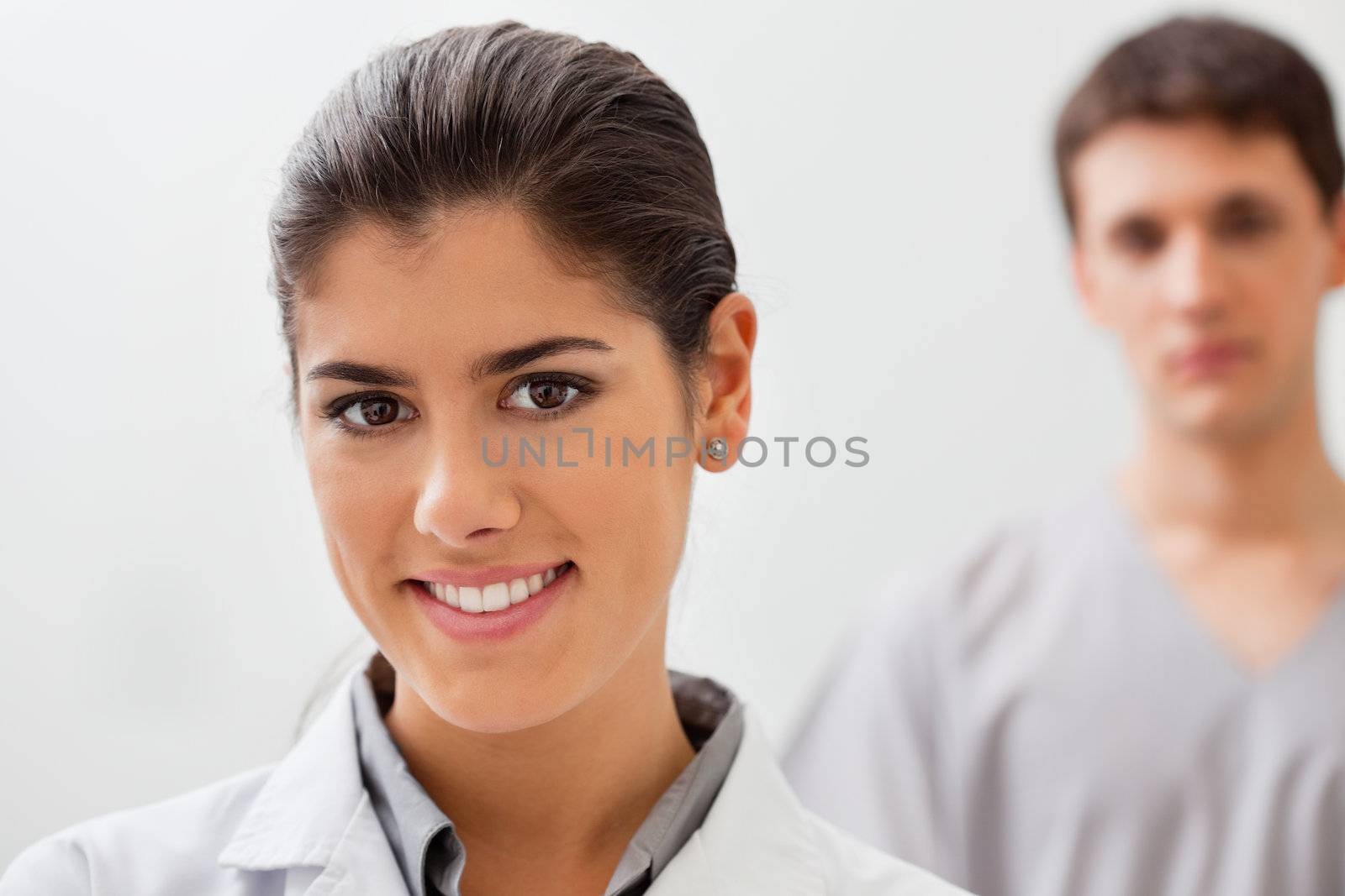 Portrait of smiling female doctor with practitioner standing in background