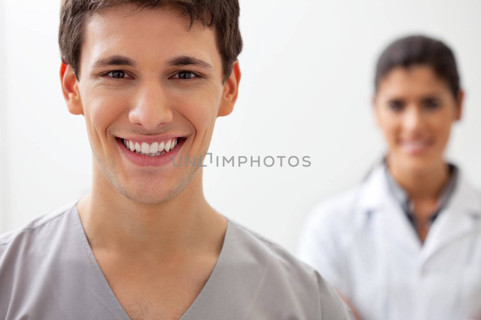 Portrait of happy male doctor standing with female doctor standing in background