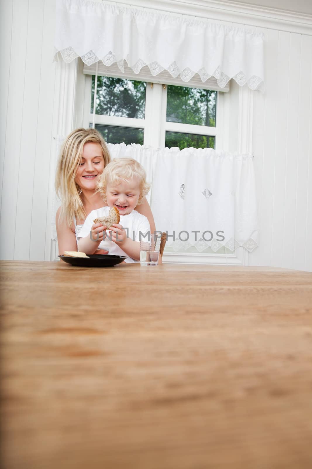 Smiling young mother with baby boy looking at bread at dining table