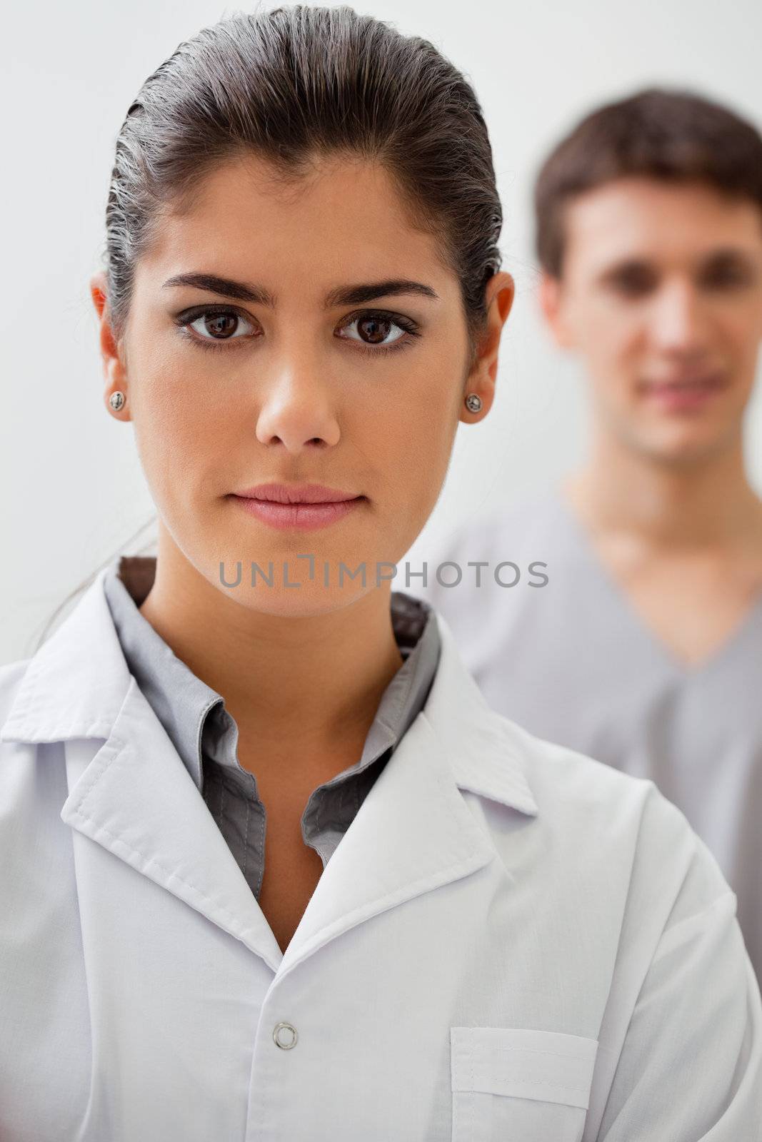 Portrait of confident female doctor with practitioner standing in background