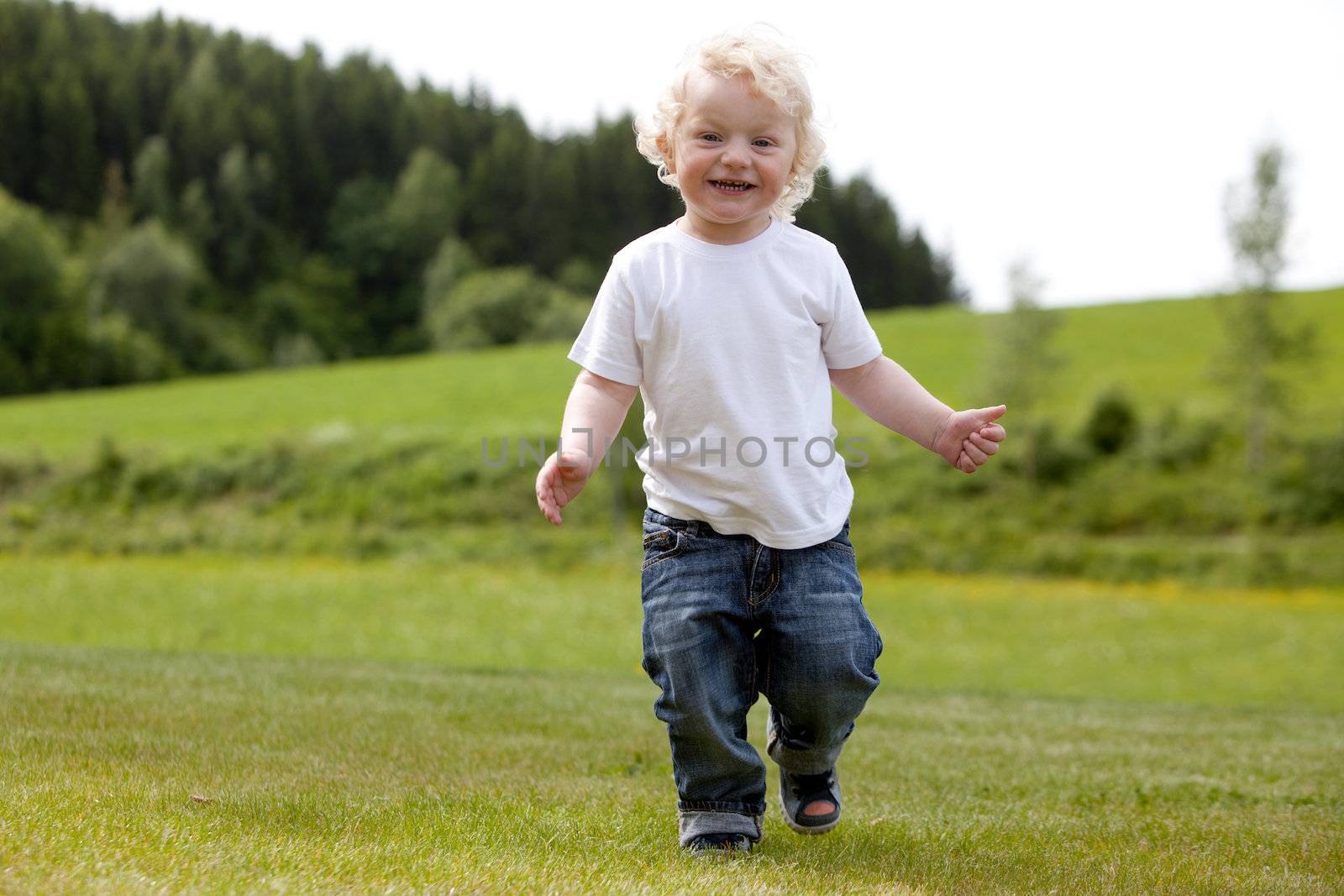 A cute smiling child running and playing outdoors in grass