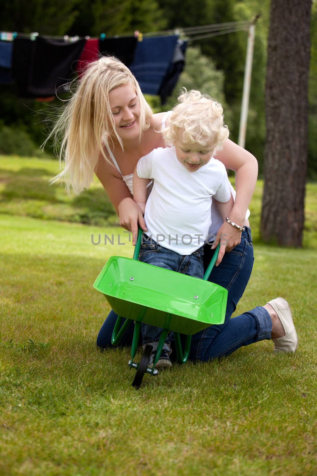 A young mother playing with her toddler son outdoors in a rural setting