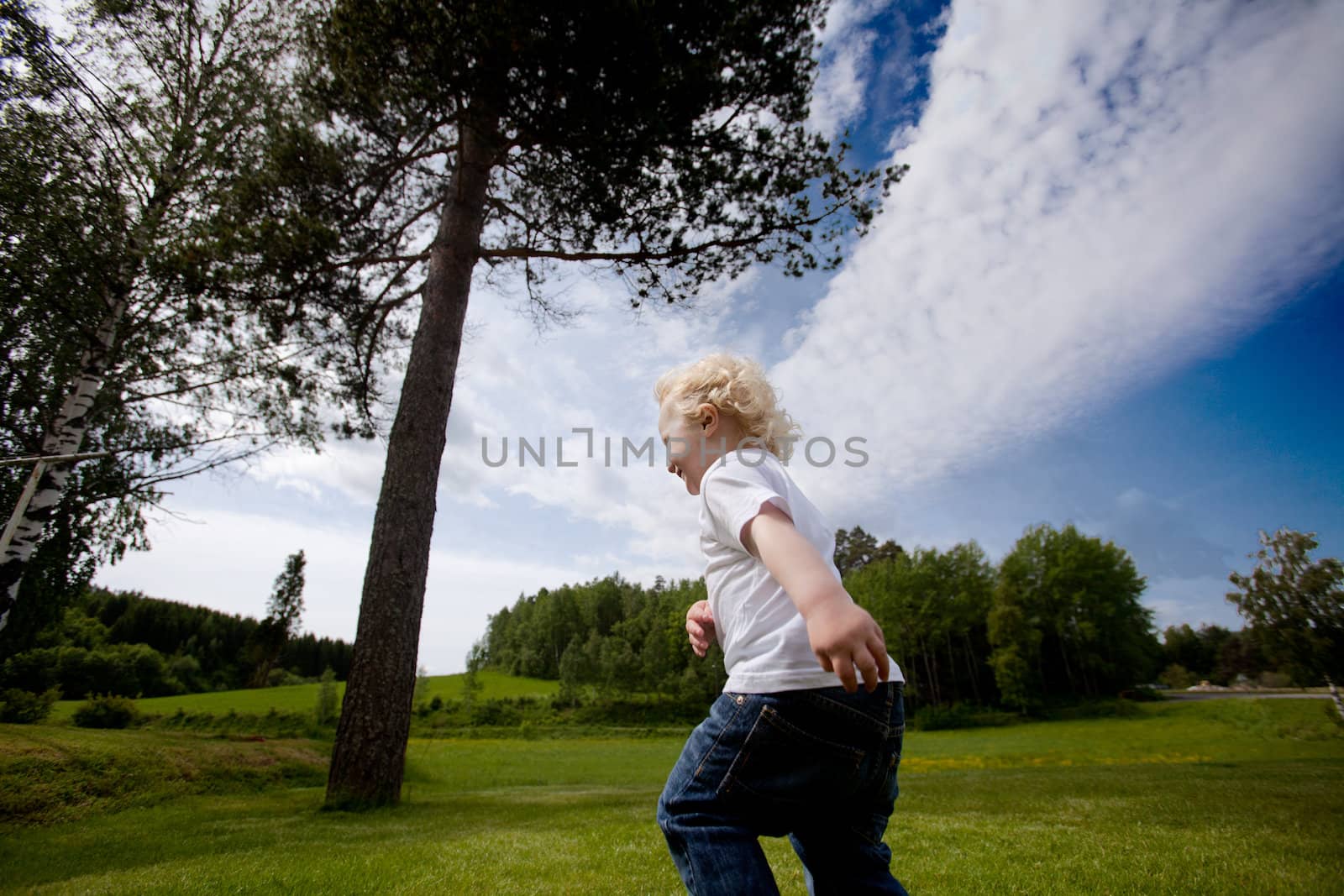 A young child running free in an open green meadow