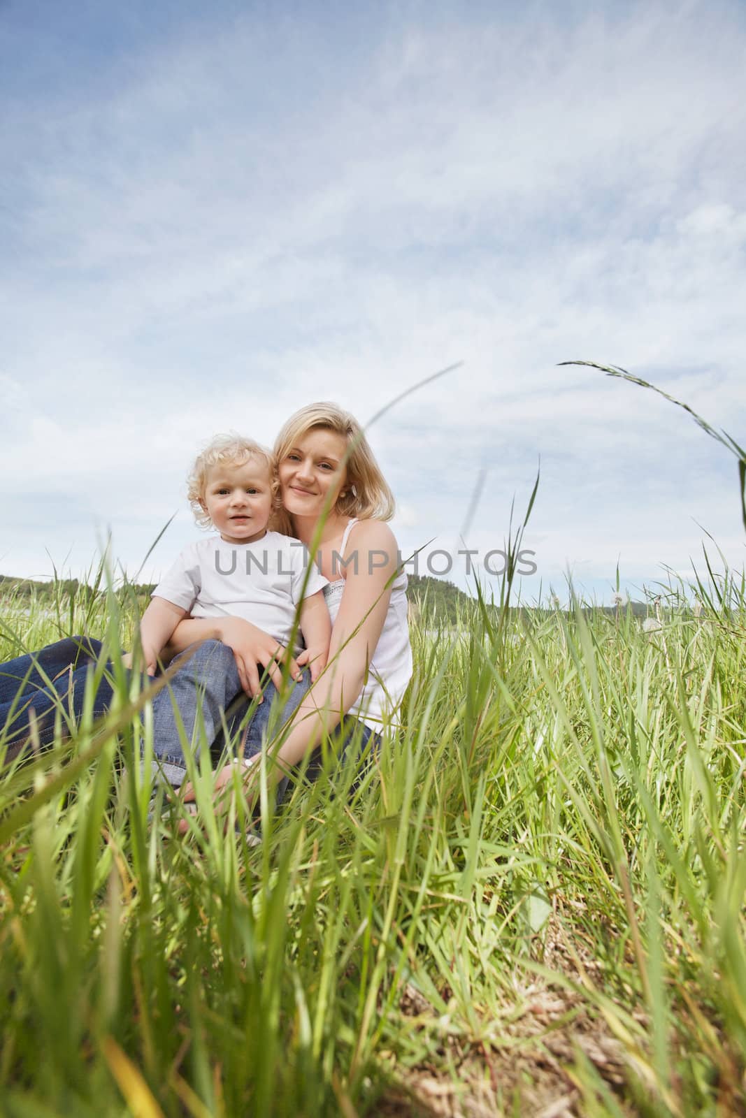 Mother sitting on grass with son by leaf