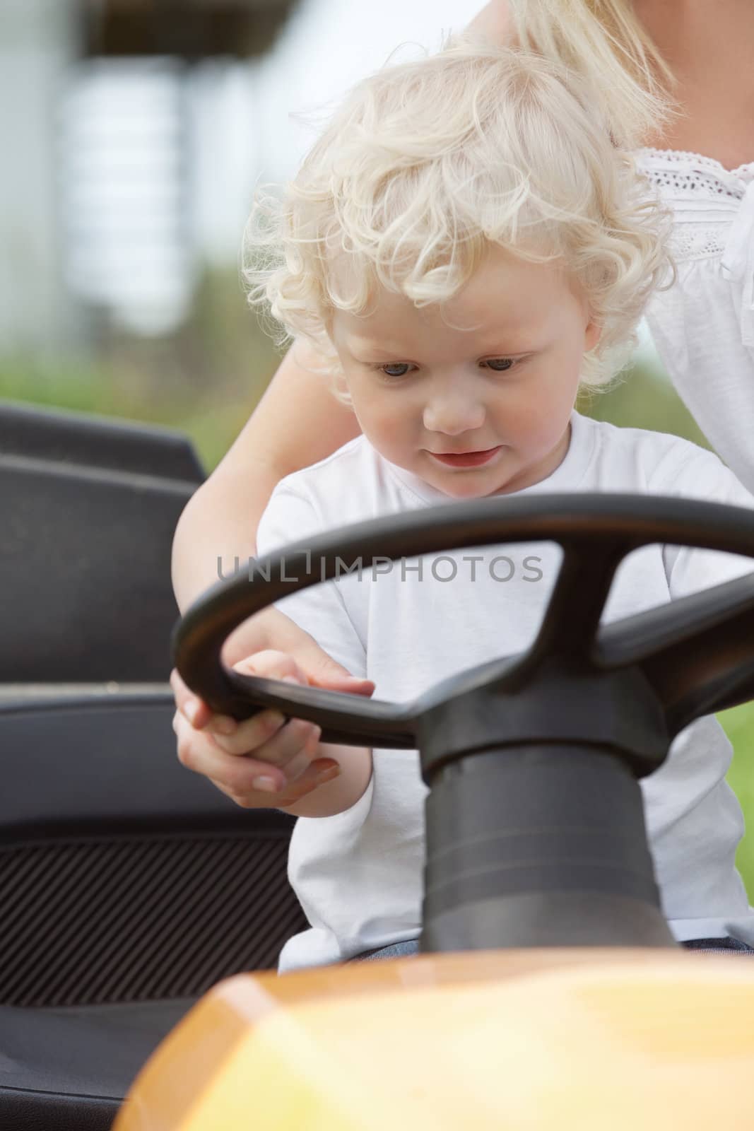 Young boy holding wheel on garden tractor