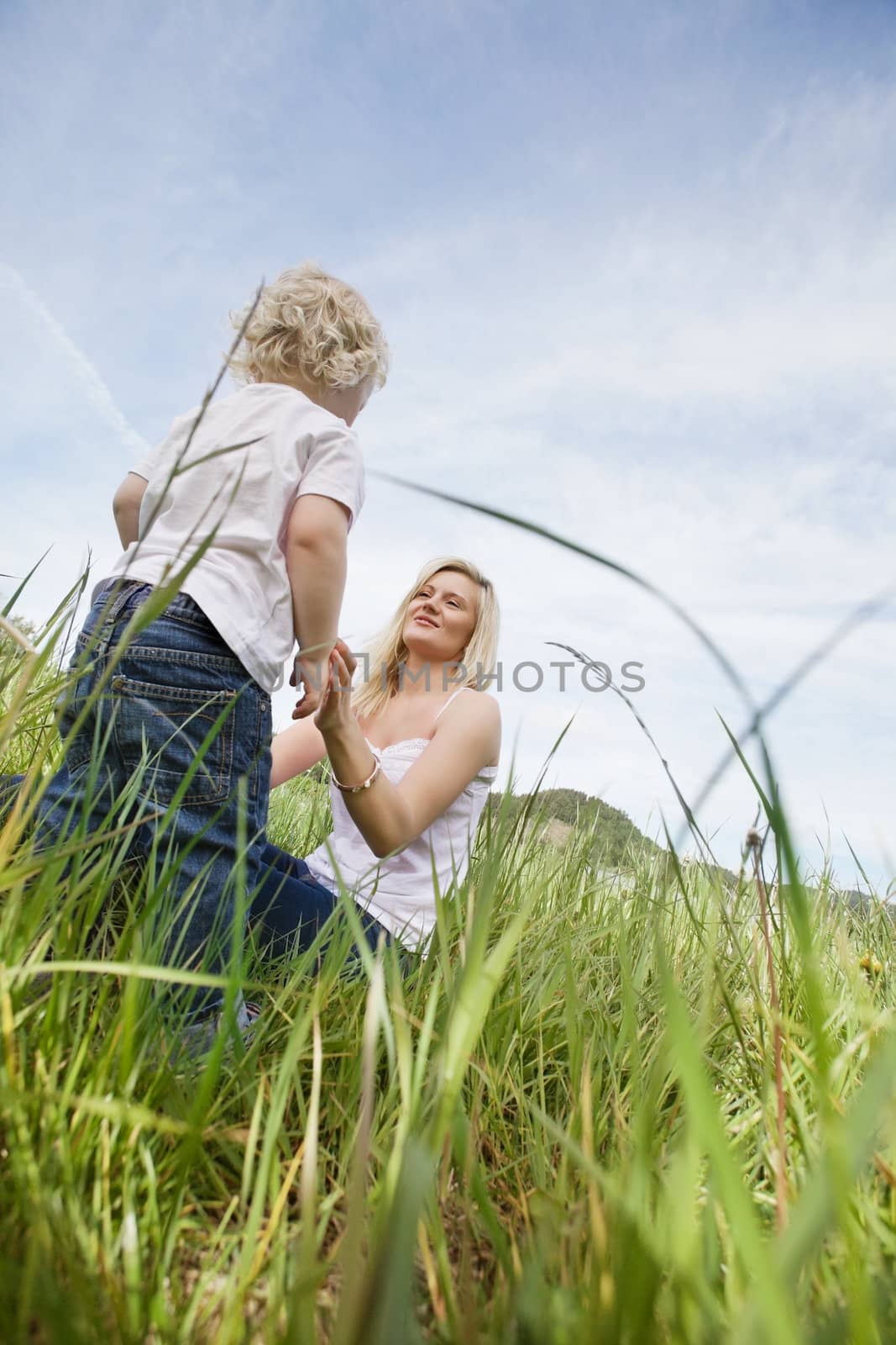 Mother and little boy in grass by leaf