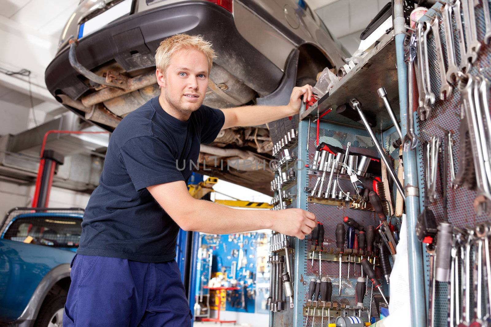 Mechanic standing beside tool chest, looking at the camera