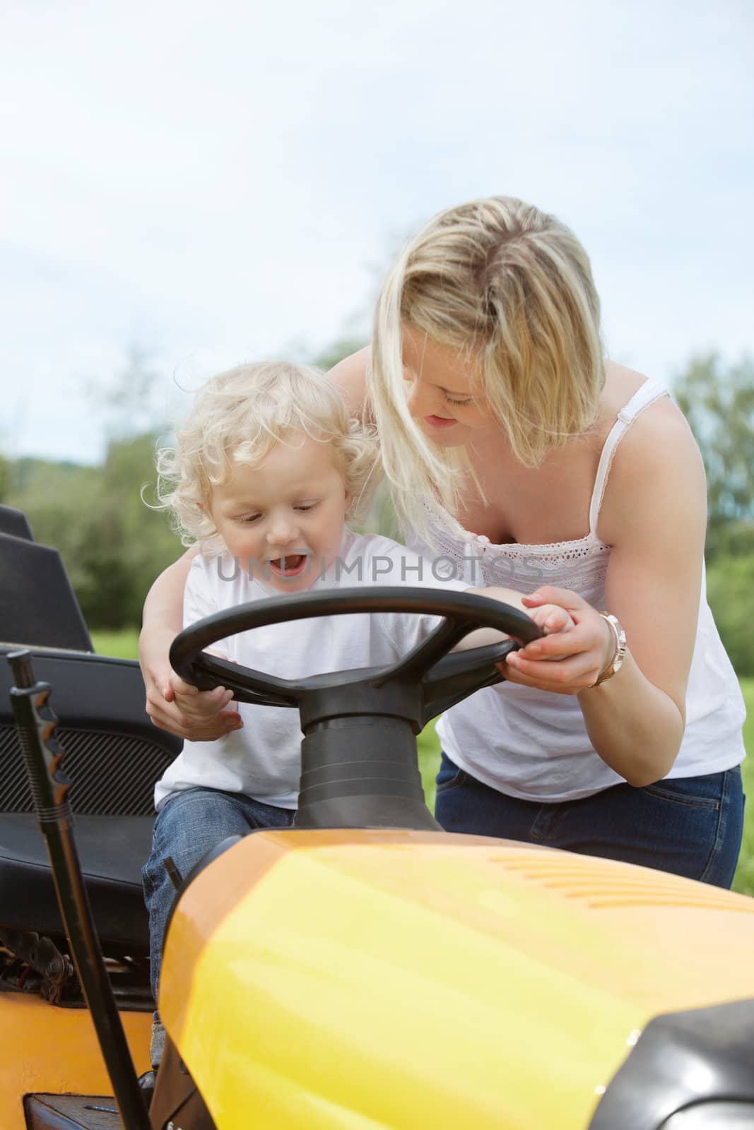 Young Boy with Mother on Garden Tractor by leaf