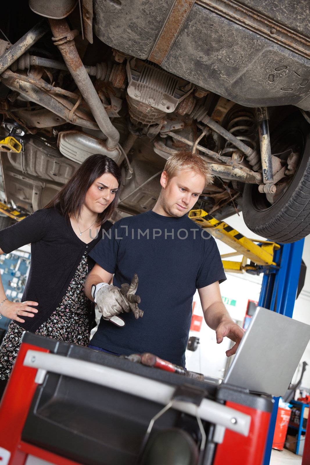Concentrated man and woman looking at laptop while standing in garage