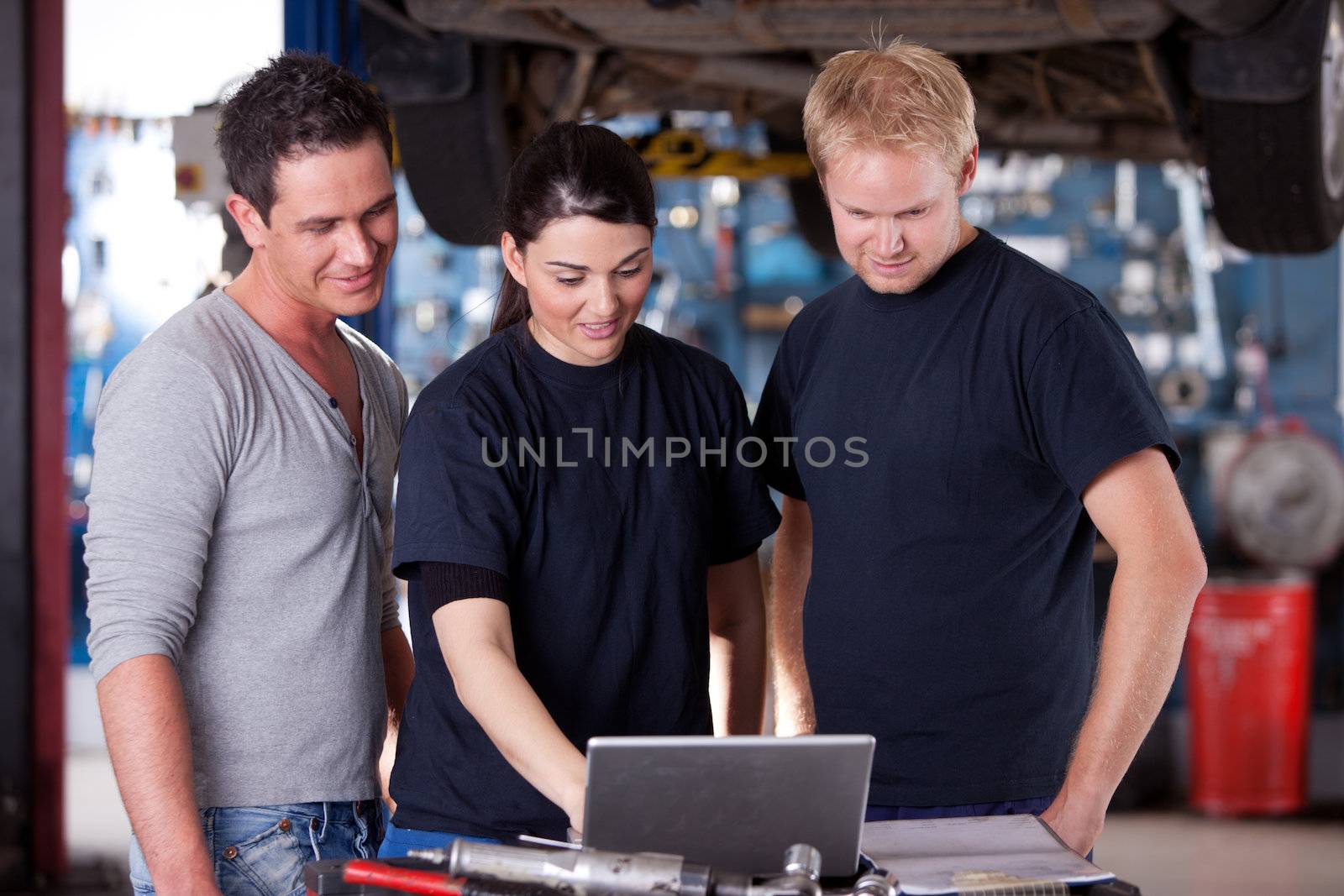 A group of mechanics referring to a laptop for service order or diagnostics results